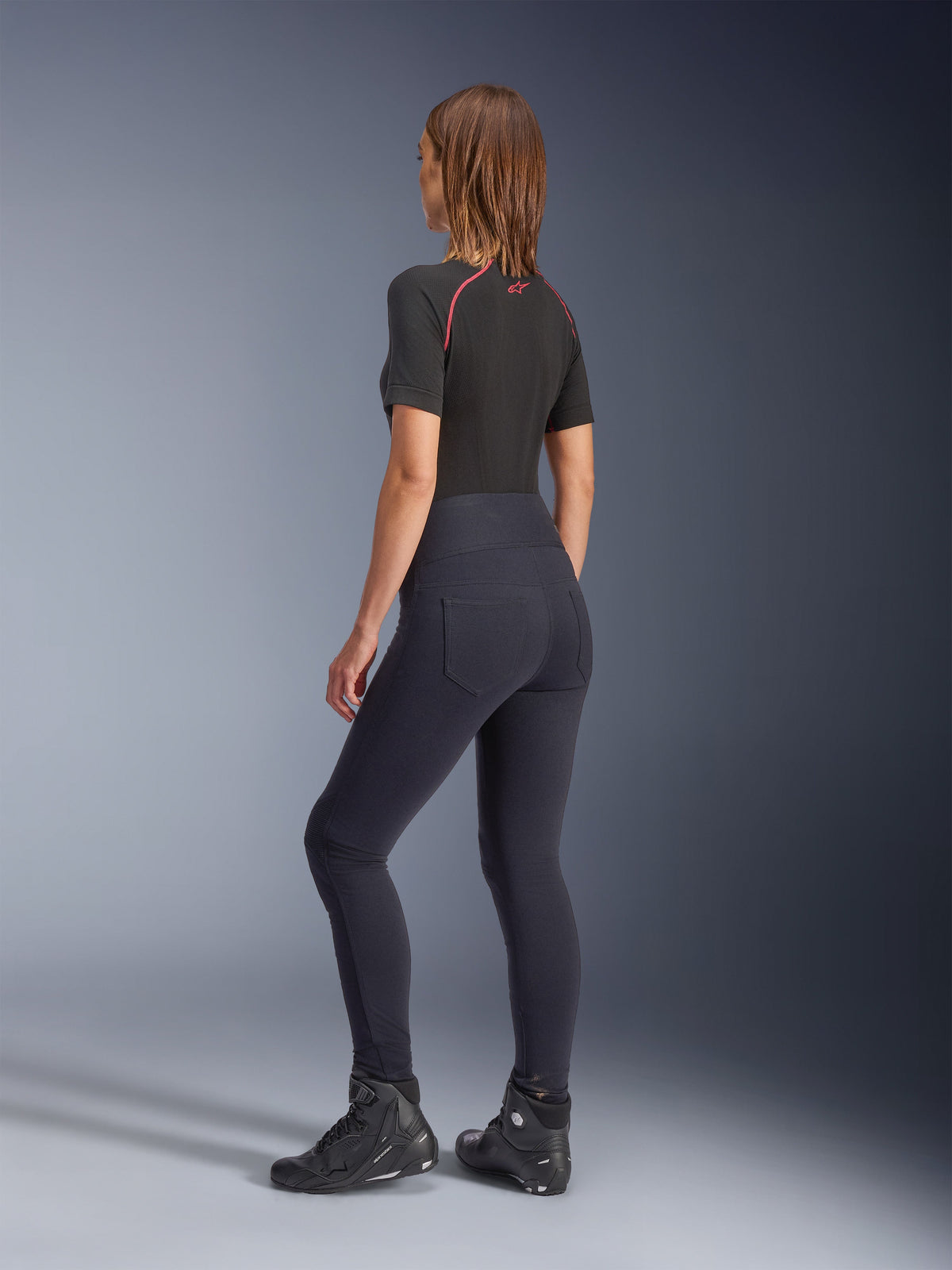 Alpinestars Stella Flex-AST Leggings för dam, svarta motorcykel-leggings med hög midja, vy bakifrån som visar tight passform och bakfickor, bärs med svart kortärmad topp och motorcykelstövlar, urban körutrustning för kvinnor.