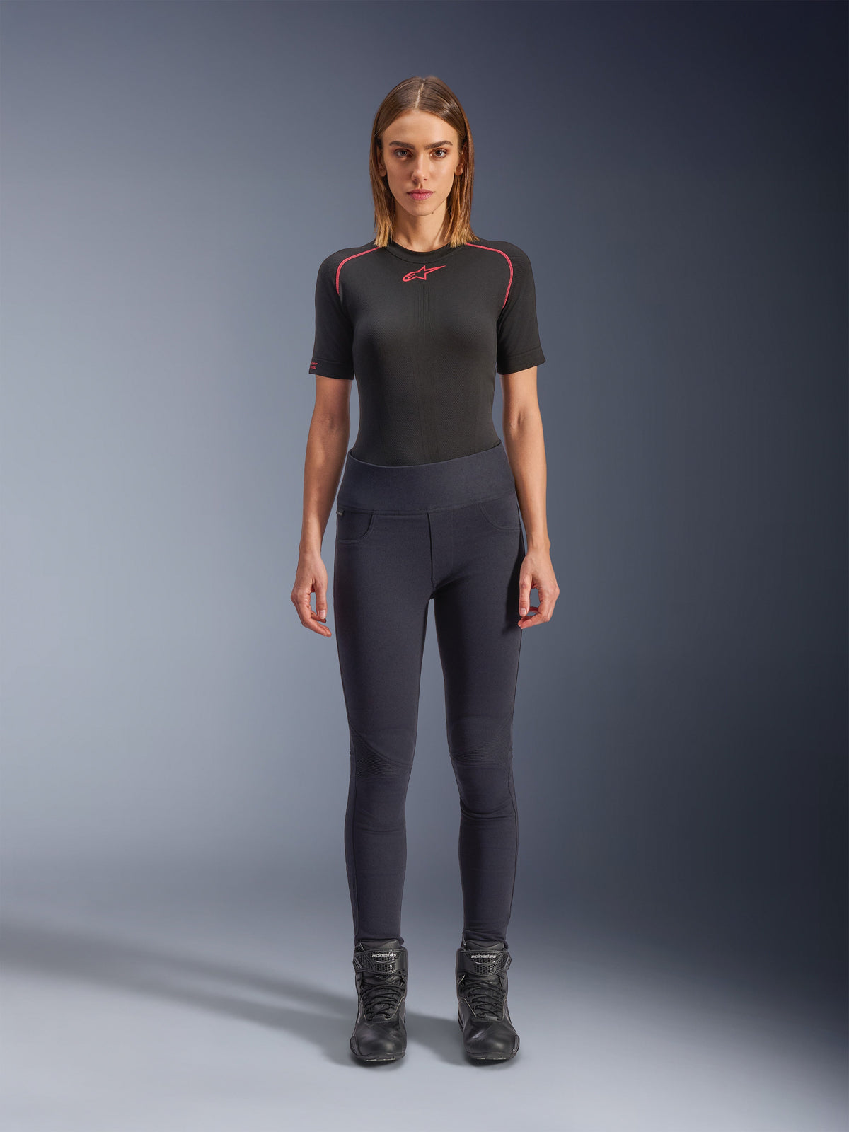 Alpinestars Stella Flex-AST Leggings, urbana mc-leggings för damer i svart, skinny-modell med hög midja bärs med en svart kortärmad teknisk topp och svarta mc-stövlar, med dragspelspaneler på knäna och en modern minimalistisk look