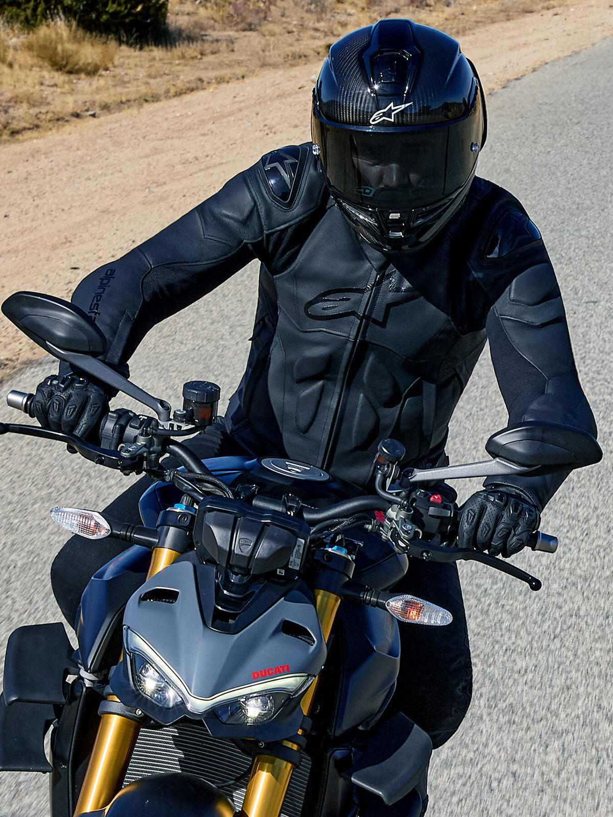 Alpinestars Dusk Leather Jacket, Black men's road racing leather jacket with shoulder sliders, riding a grey Ducati.