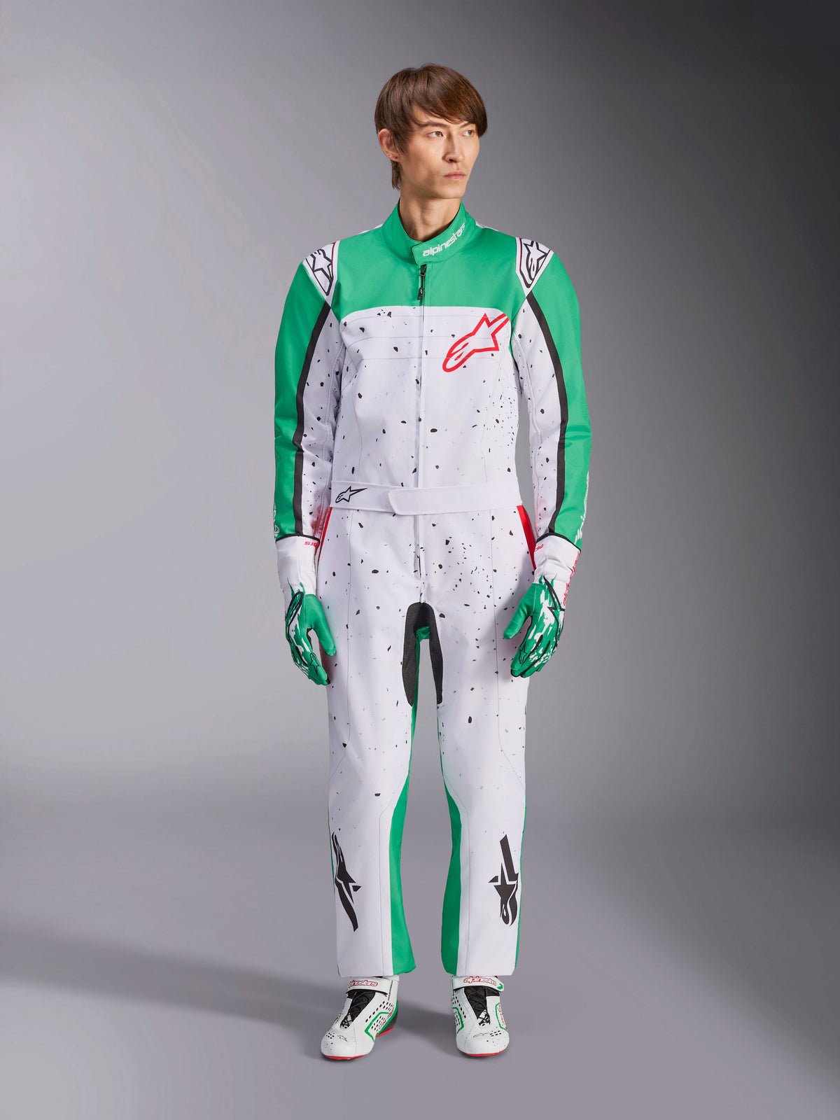 Alpinestars KMX-9 V3 Graphic 6 Suit, vit, grön och röd kartingoverall med svart splatter-mönster, gröna paneler på ärmar och ben, röd Alpinestars-logotyp på bröstet, bärs med matchande racinghandskar och skor