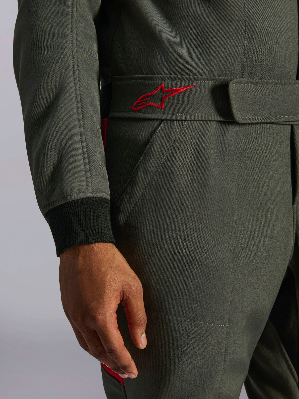 Alpinestars GP Race V3 Suit FIA, racingoverall för bil, Anthracite Red, närbild på det justerbara midjebältet med en röd broderad logotyp och en svart ribbstickad ärmmudd på texturerat twill-tyg.