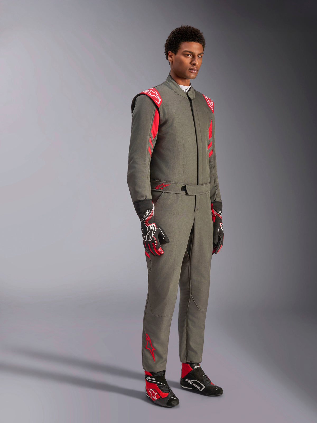 Alpinestars GP Race V3 Suit FIA, antracitröd racingoverall för bilsport, bärs med matchande racinghandskar och skor, med röda axelklaffar och logotyper, stilren teknisk tvålagersdesign för motorsport