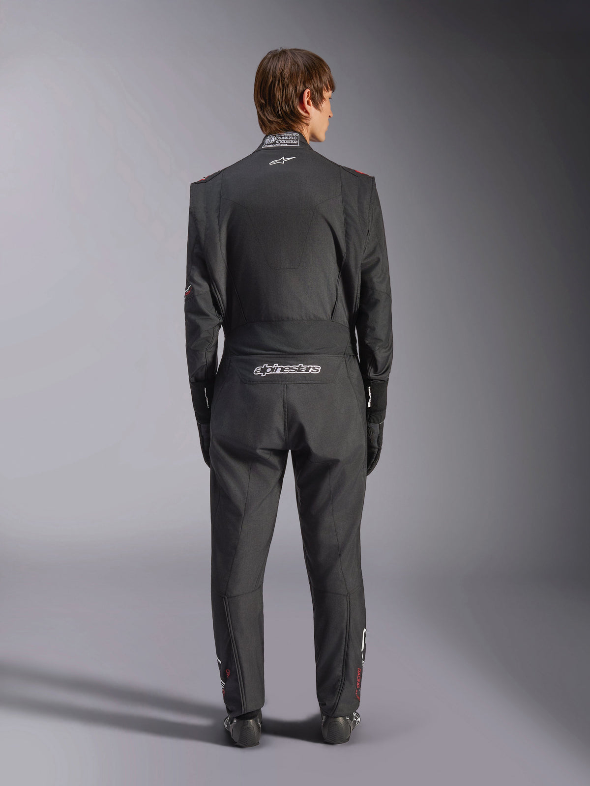 Alpinestars GP Tech V4 Suit, Auto Racing Suit, Black and White, back view featuring white Alpinestars branding and FIA certification on the collar, sleek ergonomic fit for professional driver protection