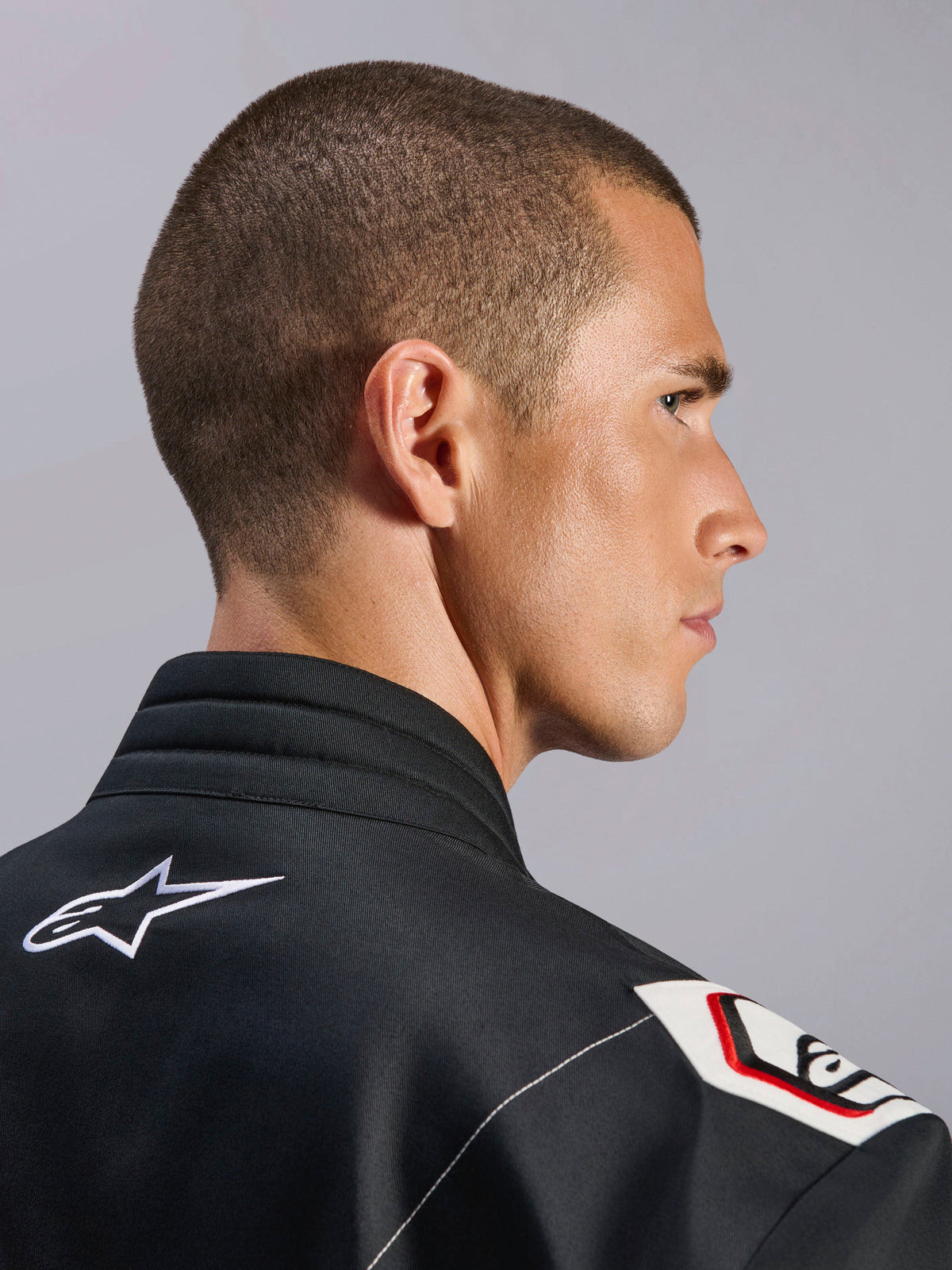 Alpinestars Kart Indoor V2-overall, svart, närbild på den ergonomiska kragen och Formel 1-inspirerad axeldesign, med vit Alpinestars-logotyp och racinginspirerade detaljer på slitstarkt twillmaterial