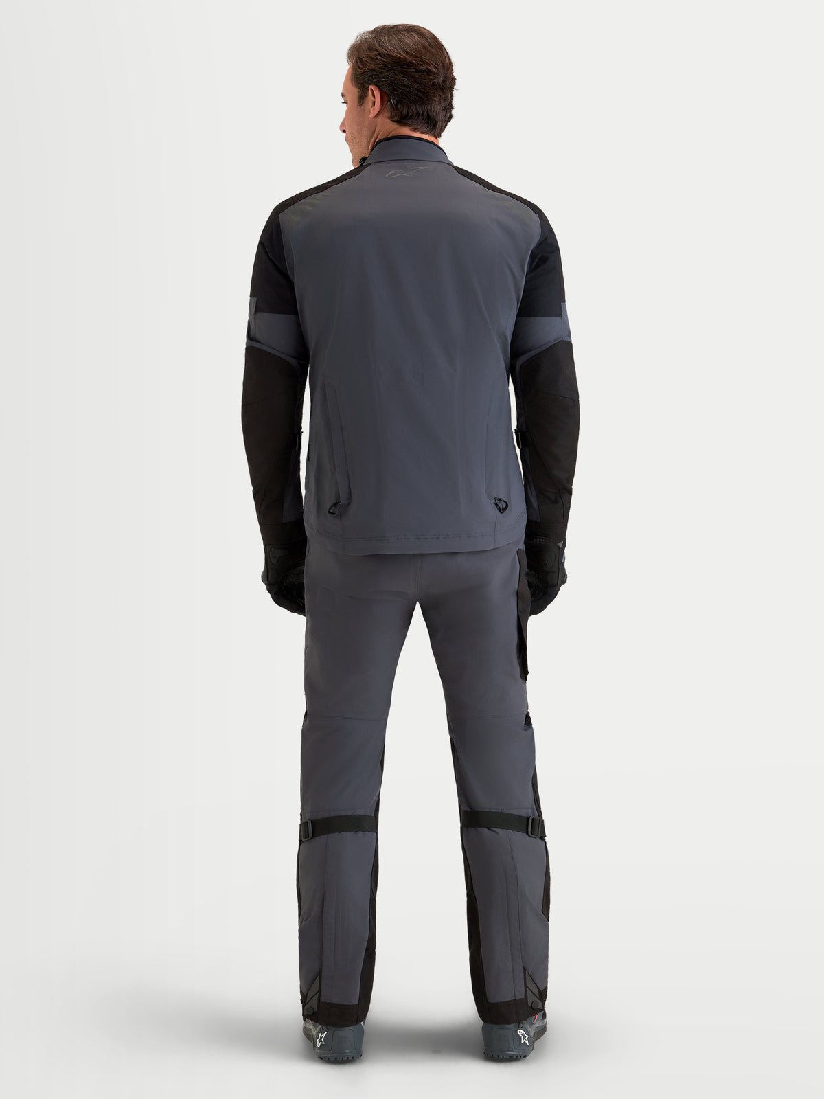 Alpinestars Arenis Gore-Tex Gear Set, grå och svarta äventyrsmotorcykelkläder för herr, vy bakifrån på modell som bär vattentät utrustning för alla terränger