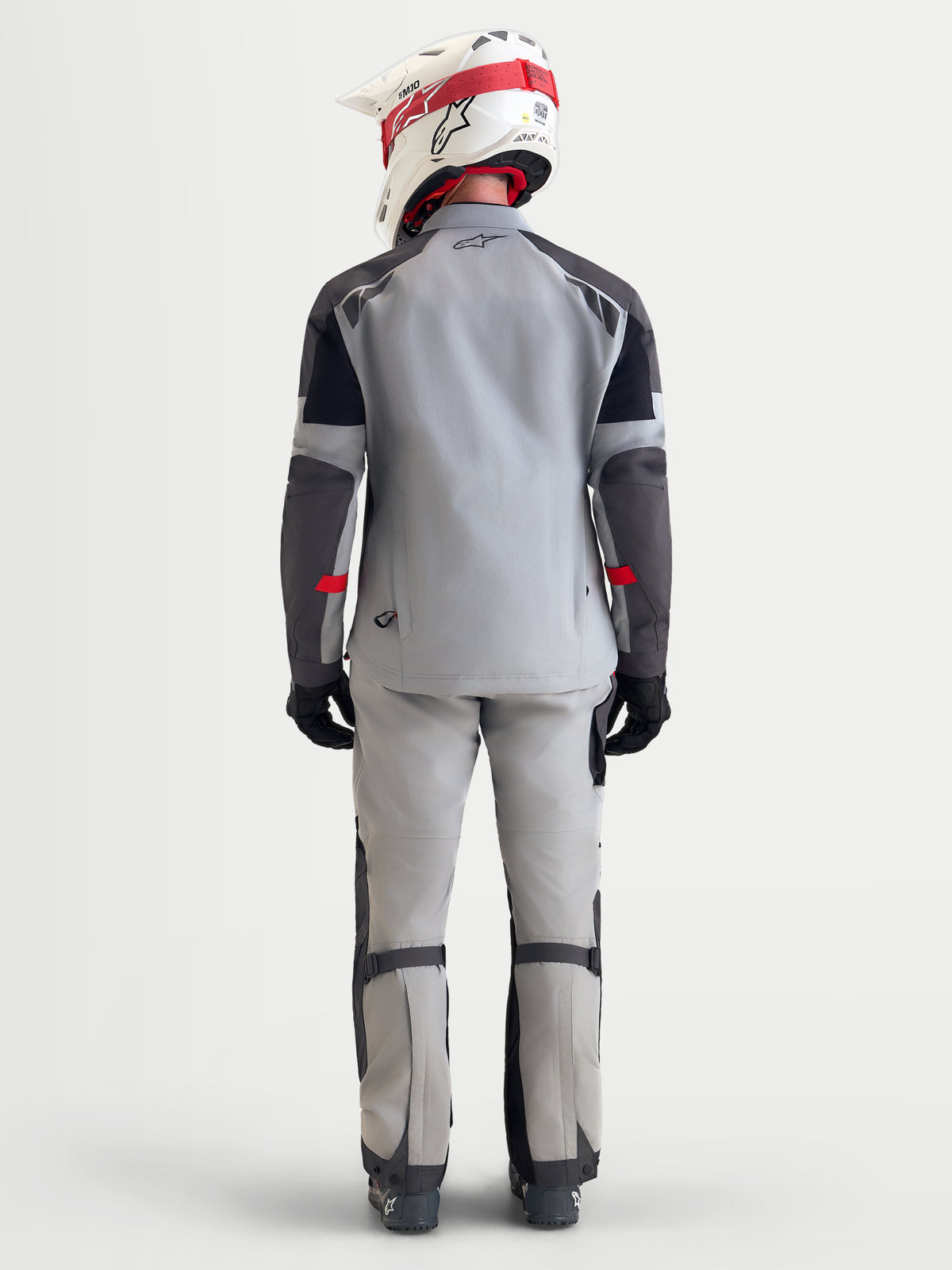 Alpinestars Arenis Gore-Tex jacka, äventyrsmotorcykeljacka för herr i mellergrå, mörkgrå och svart, vy bakifrån som visar en modell som bär den vattentäta textiljackan med hjälm och körutrustning