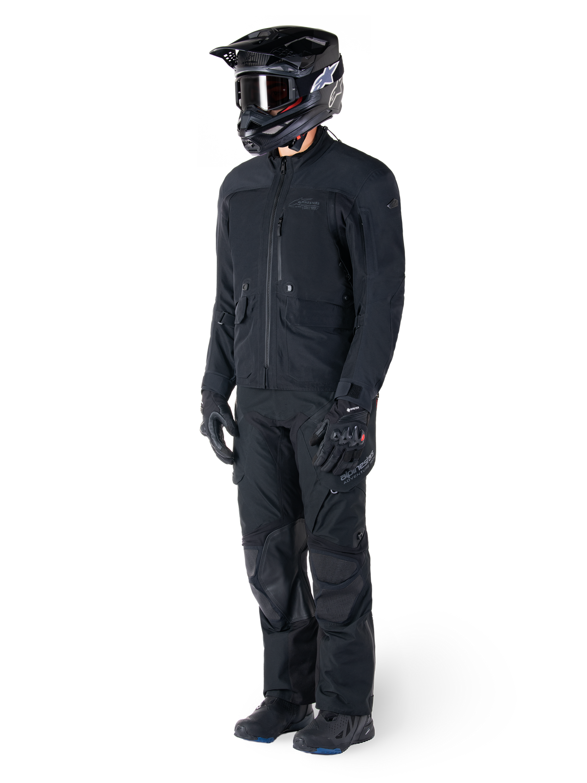 Motorcyklist klädd i Alpinestars St-7 Prime GORE-TEX-jacka i svart, matchande adventure touring-outfit med svarta byxor, svart hjälm med goggles och handskar, med en strömlinjeformad och funktionell design för prestanda i alla väder.