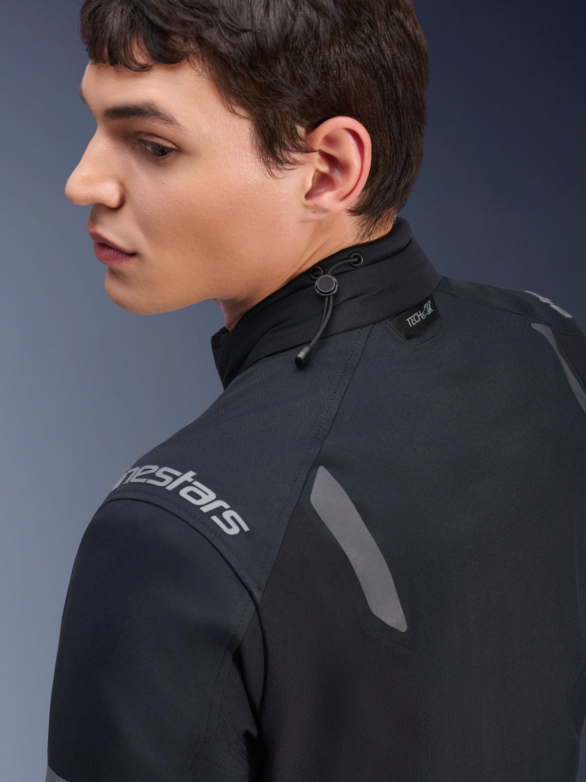 Alpinestars ST-7 2L GORE-TEX-jacka, svart och mörkgrå motorcykeljacka, närbild av kragen som visar justering med dragsko och Tech-Air-etikett, med grå reflexdetaljer och logotyp på axeln.