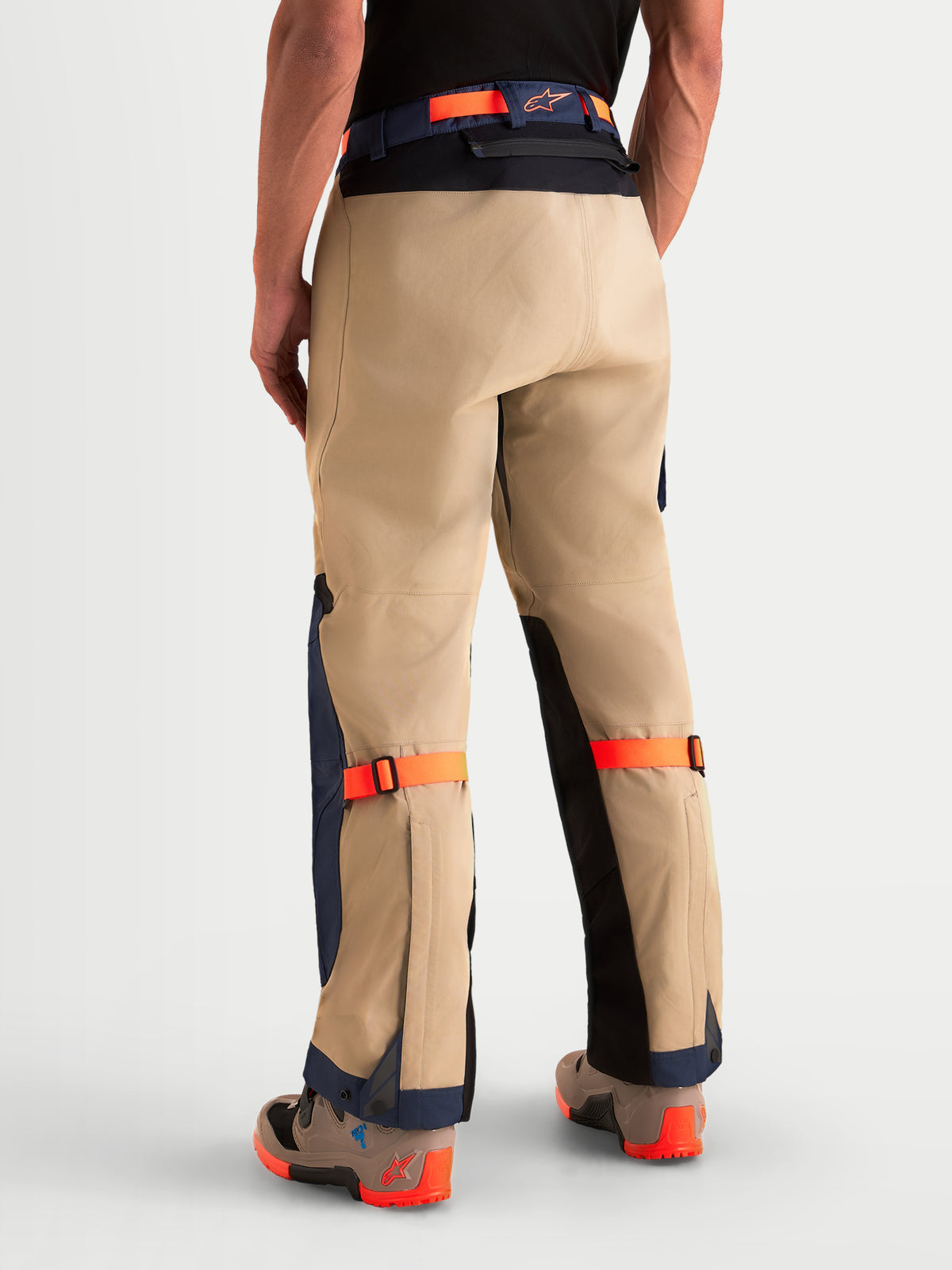 Alpinestars Arenis Gore-Tex byxor, äventyrsmotorcykelbyxor för herr i beige, mörkblått och orange, vy bakifrån på modell som visar vattentät texturkonstruktion, förstärkt säte och justerbara remmar