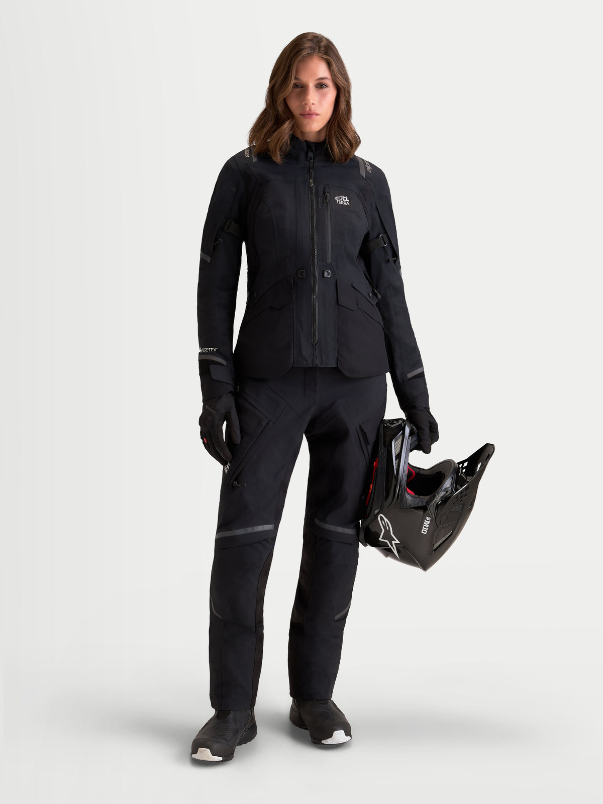 Alpinestars Stella ST-7 V2 2L Gore-Tex byxor, svarta äventyrsmotorcykelbyxor för dam, framifrån på modell som bär matchande utrustning och håller en hjälm