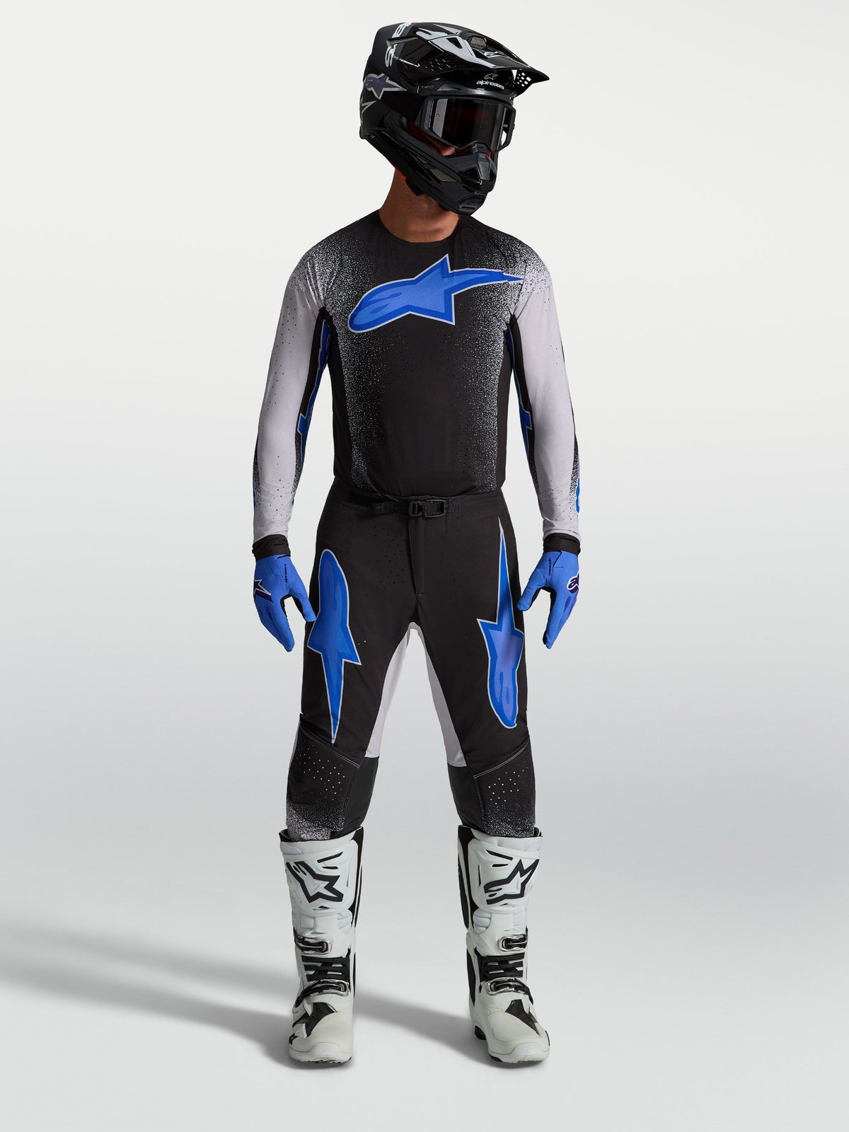 Alpinestars Supertech Hiten AFD byxor, svarta och blåa motocrossbyxor på modell med matchande tröja och vita racingstövlar.