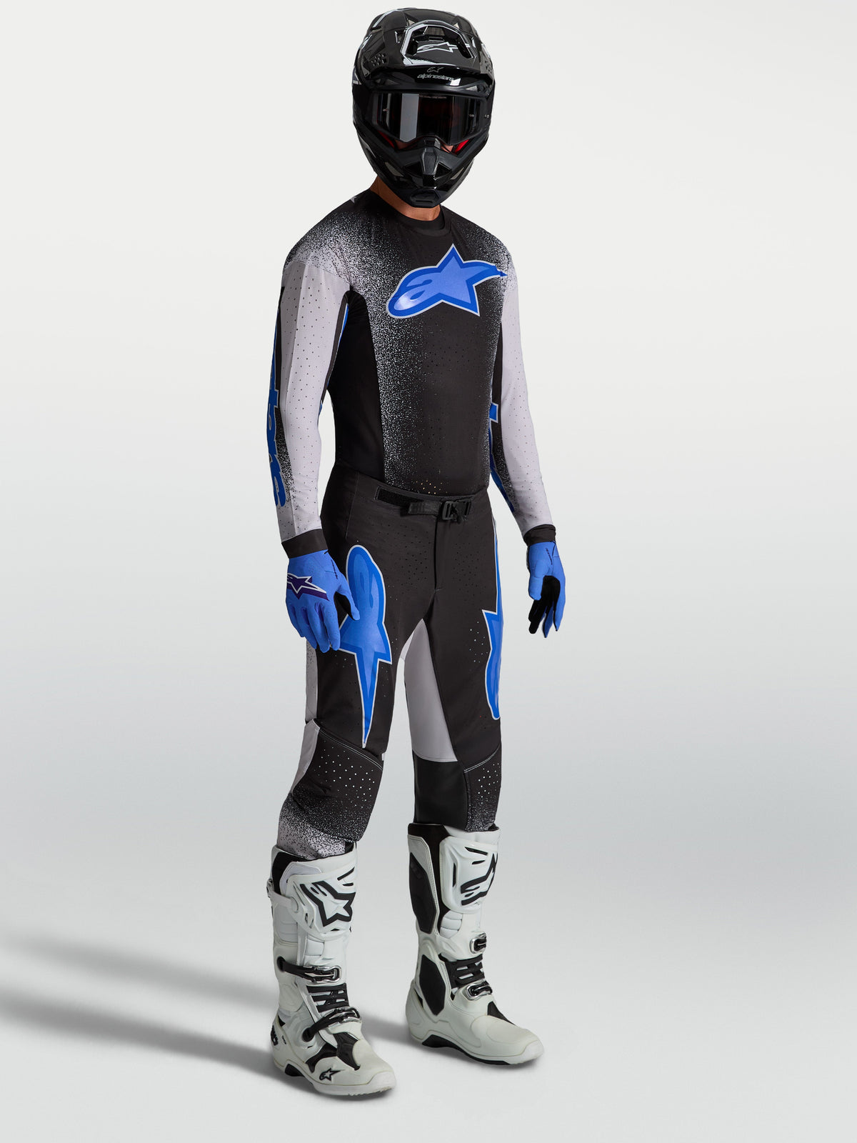 Alpinestars Supertech Hiten AFD byxor, motocrossbyxor på modell med matchande tröja och vita stövlar, svarta och blå.