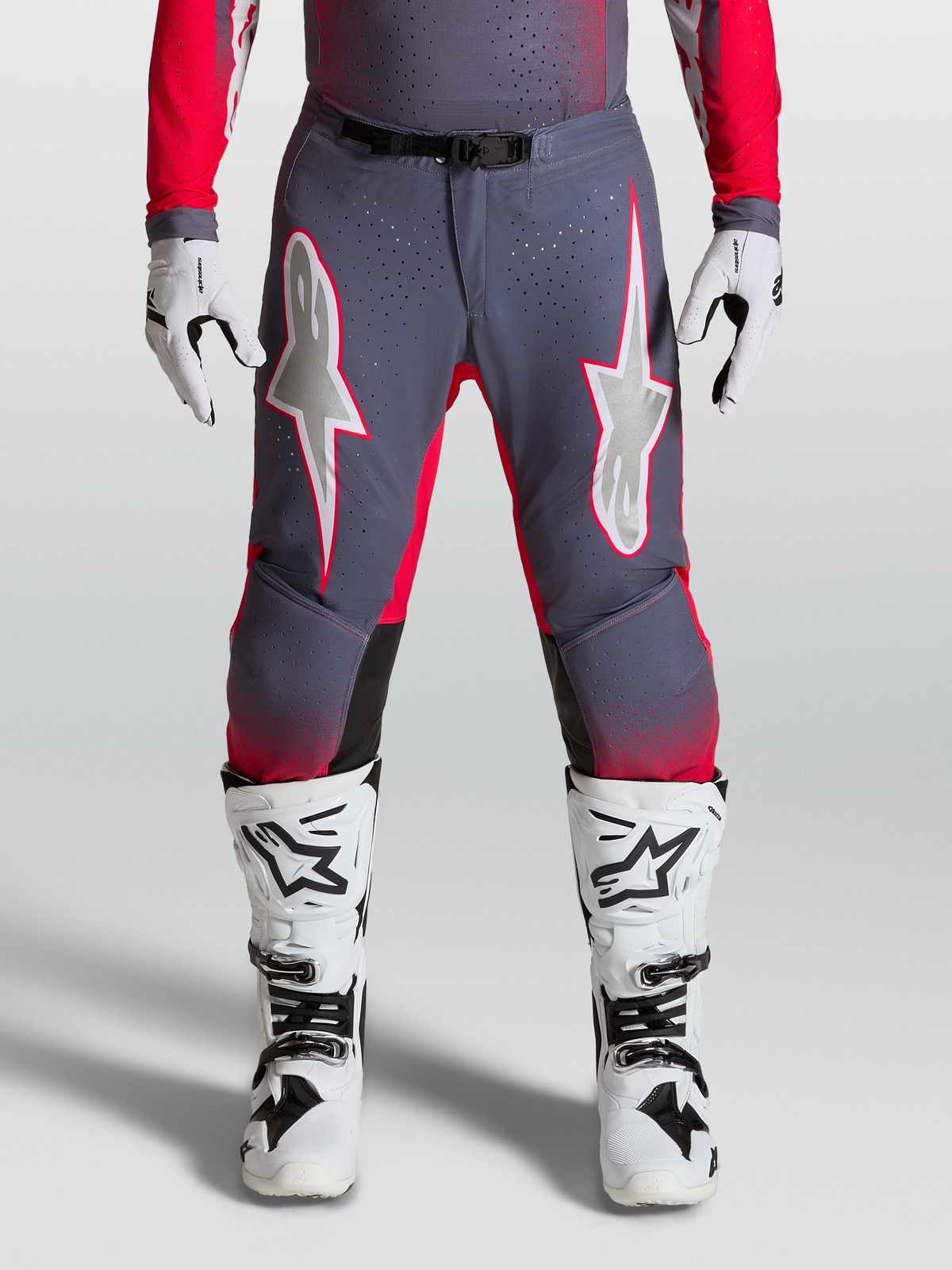Alpinestars Supertech Hiten AFD Byxor, gråa och röda motocrossbyxor med lila stjärngrafik och perforerade paneler för elitförare.