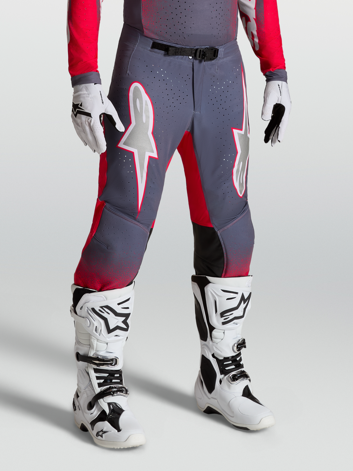 Alpinestars Supertech Hiten AFD Byxor, gråa och röd fluo motocrossbyxor med vit stjärngrafik och magnetiskt spänne, bärs med vita stövlar