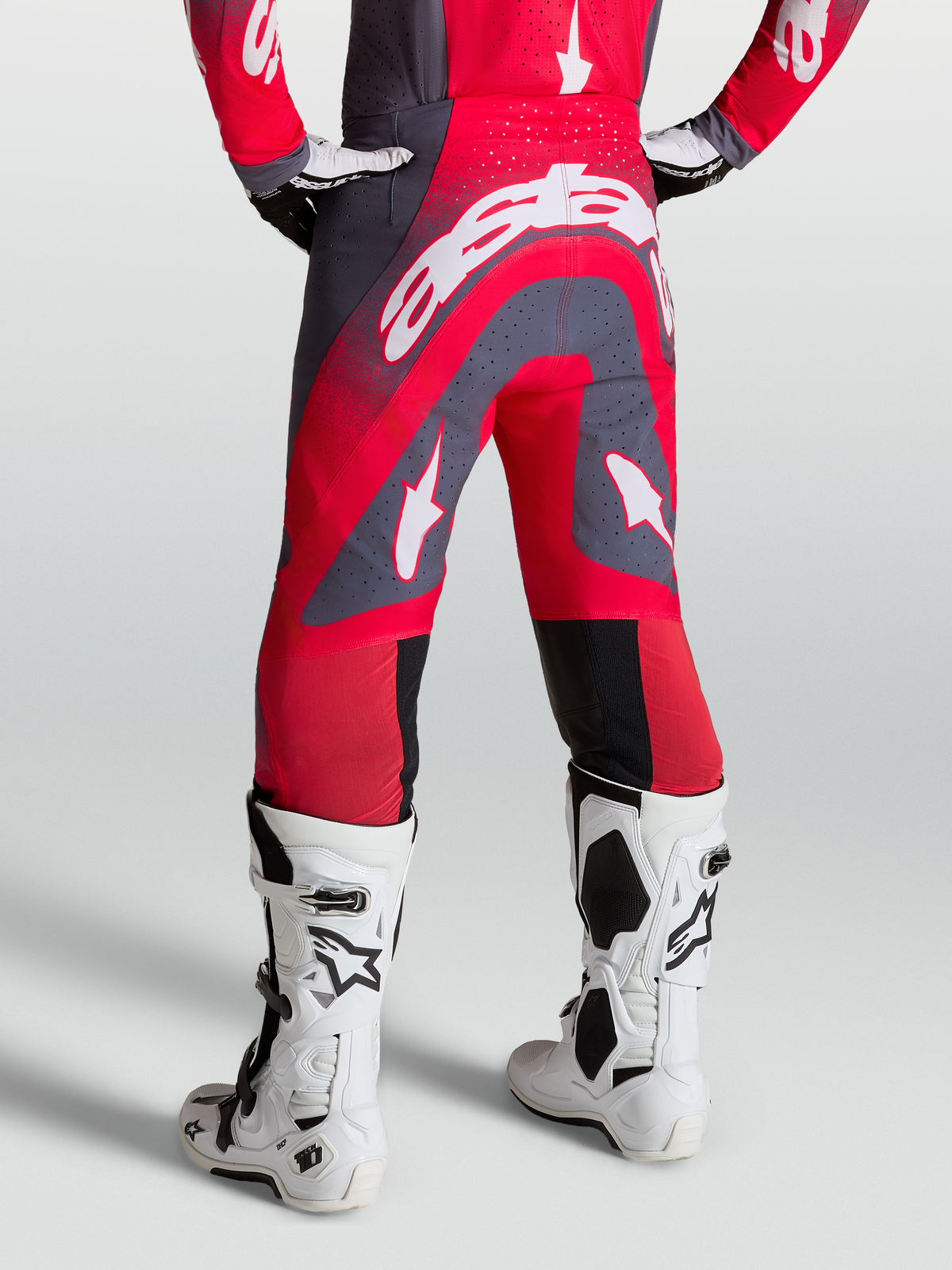 Alpinestars Supertech Hiten AFD Byxor, röda och grå motocrossbyxor, vy bakifrån på modell med vita racingstövlar för terrängkörning