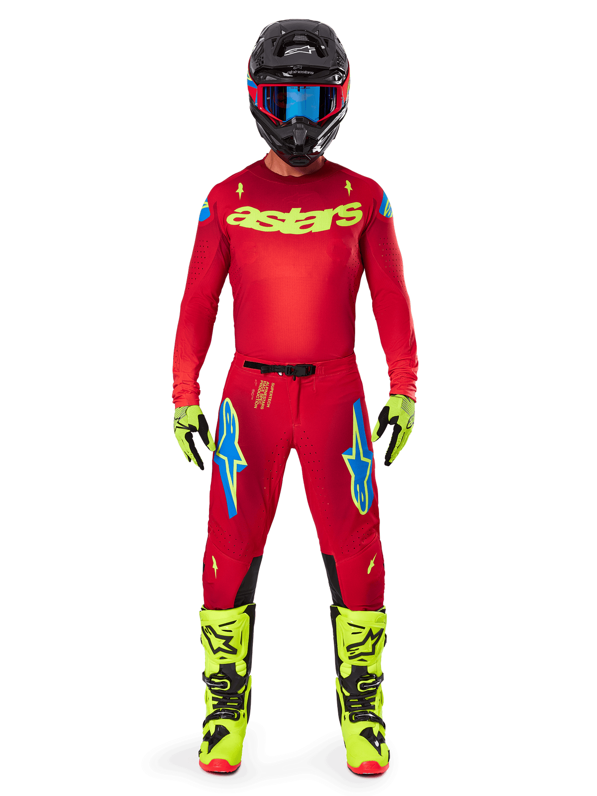 Motocrossförare i komplett racingutrustning, röd tröja med neongul astars-logotyp, Alpinestars 2025 Supertech Maker-byxor i Bright Red och Yellow Fluo med blå logotyper på låren, neongula handskar och stövlar, svart hjälm med blå goggles, koordinerad motocrossoutfit på proffsnivå