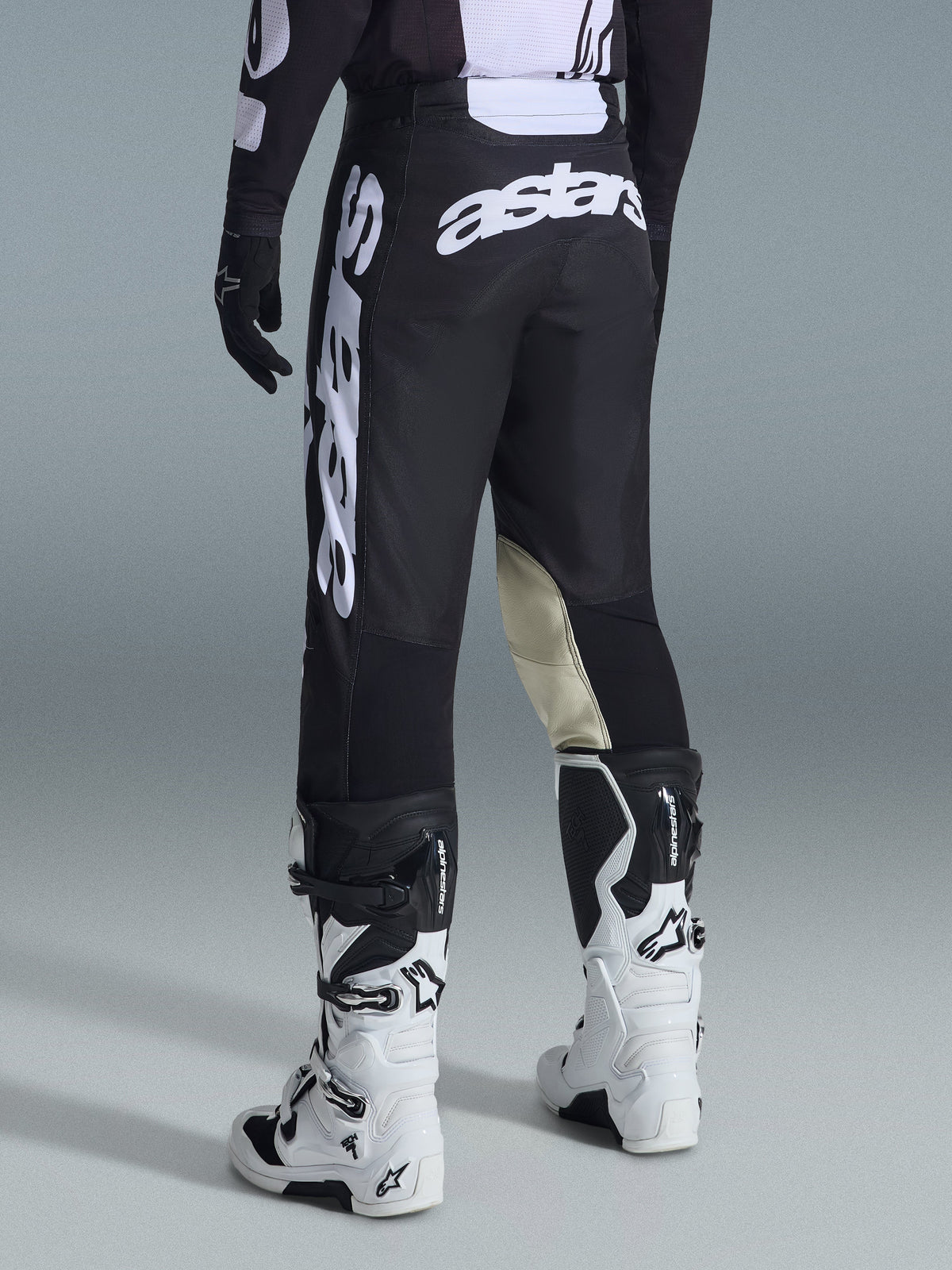 Alpinestars 2026 Racer Air Riway byxor, motocrossbyxor, svarta och vita, vy bakifrån med stor vit Astars-logotyp på sätet och benen, beige läderpaneler på knänas insida, bärs med vita och svarta Tech 7-stövlar, premium racingutrustning för terrängkörning