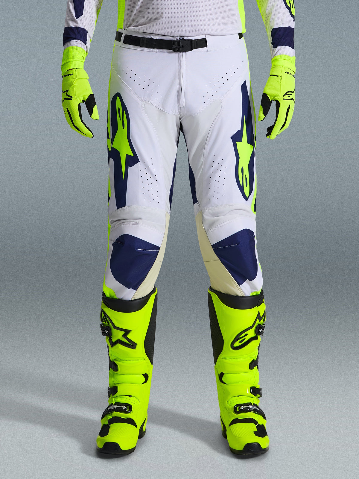Alpinestars 2026 Racer Air Riway byxor, motocrossbyxor, ljusgrå, neongula och blå, bärs med matchande neongula handskar och stövlar, med perforerade frontpaneler för luftflöde och tydlig blå och gul logotyp, atletisk design för terrängkörning