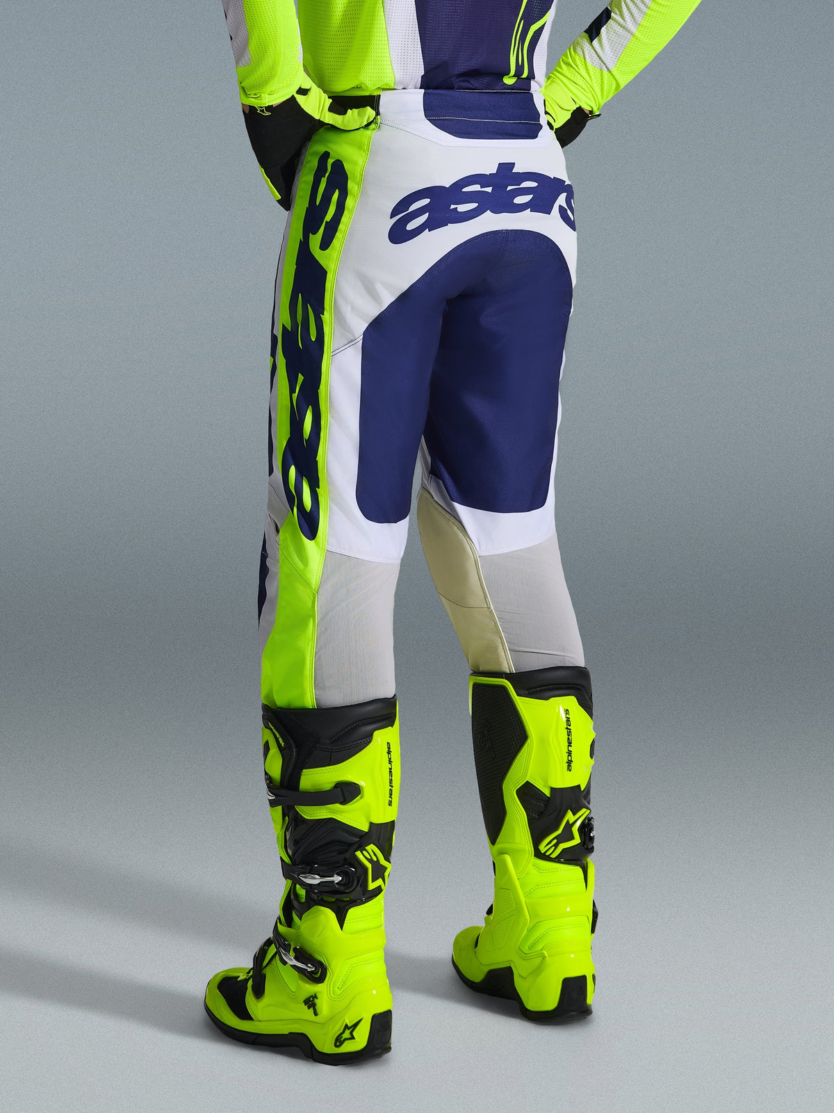 Alpinestars 2026 Racer Air Riway byxor, motocrossbyxor, ljusgrå, neongula och blå, baksida som visar tydlig blå logotyp på sätet, bärs med matchande tröja och neongula stövlar, ergonomisk racingpassform