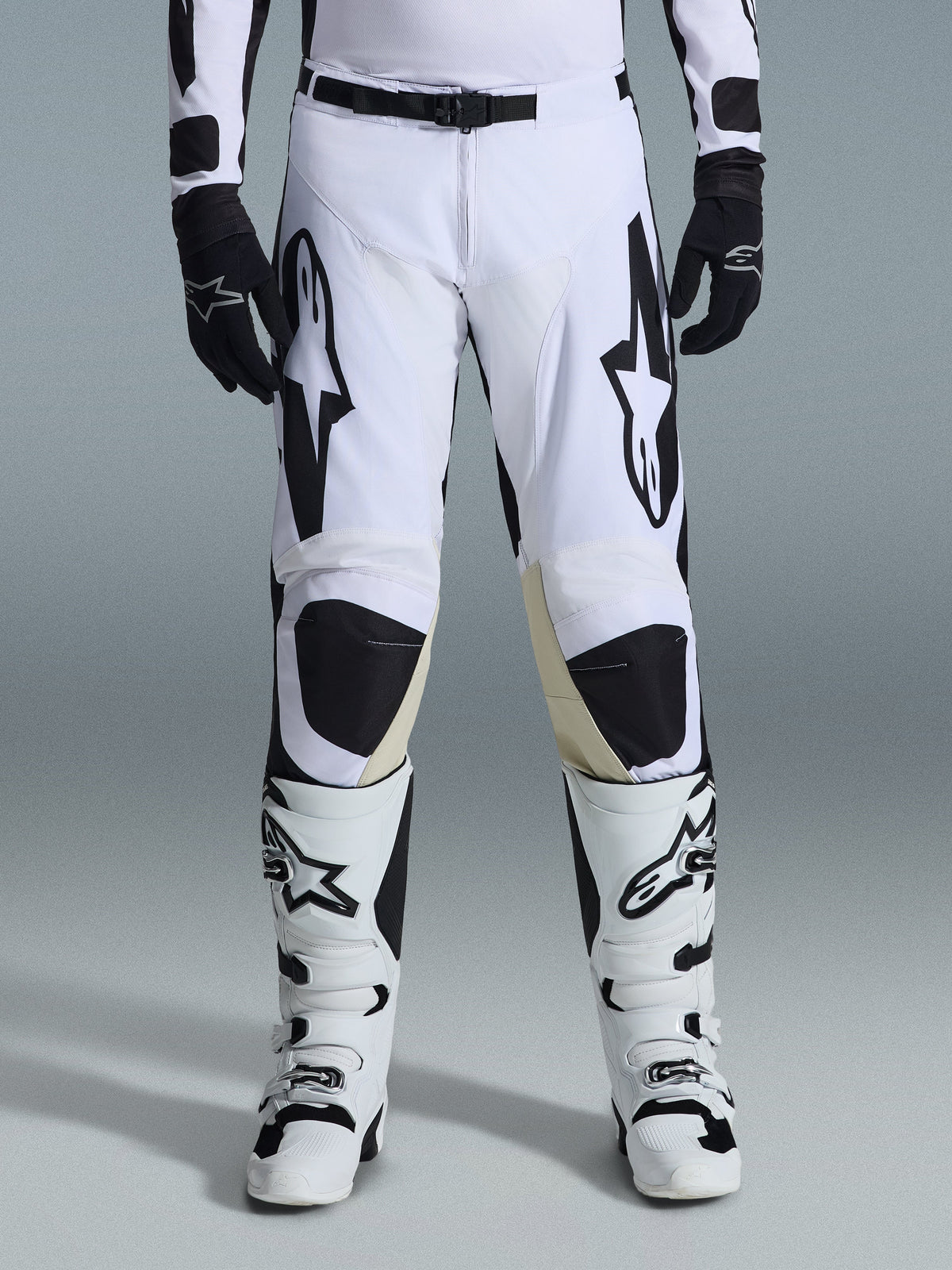 Alpinestars 2026 Racer Riway byxor, motocrossbyxor, vita och svarta, bärs med matchande vita och svarta motocross-stövlar och svarta handskar, med framträdande svart Alpinestars-logotyp på låren, teknisk design för offroad-prestanda.