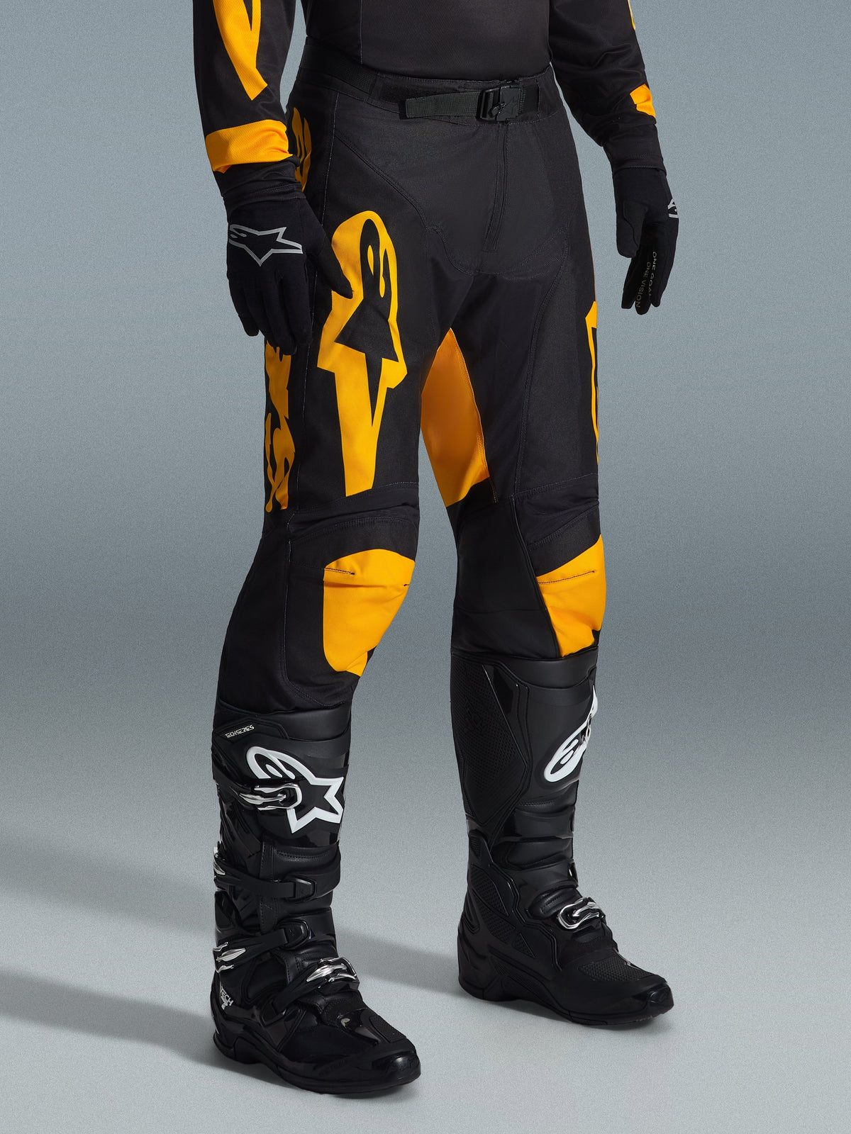 Alpinestars 2026 Racer Riway byxor, motocrossbyxor, gula och svarta, bärs med svarta handskar och svarta motocross-stövlar, med framträdande gul Alpinestars-logotyp och knädetaljer på en svart bas, designade för högpresterande terrängkörning