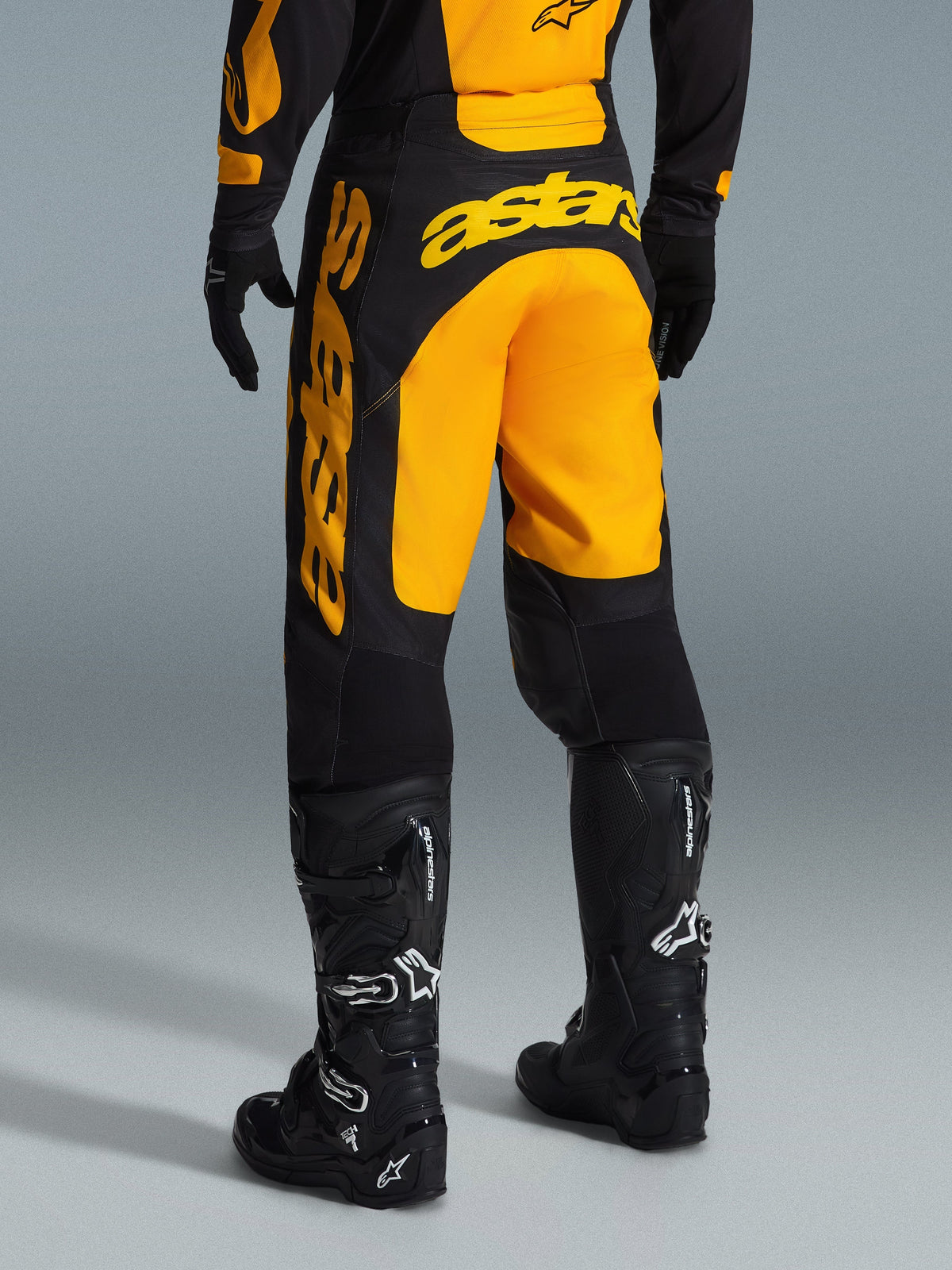 Alpinestars 2026 Racer Riway byxor, motocrossbyxor, gula och svarta, vy bakifrån som visar tydlig gul astars-branding över sätet och benet, kombinerat med svarta motocross-stövlar och handskar