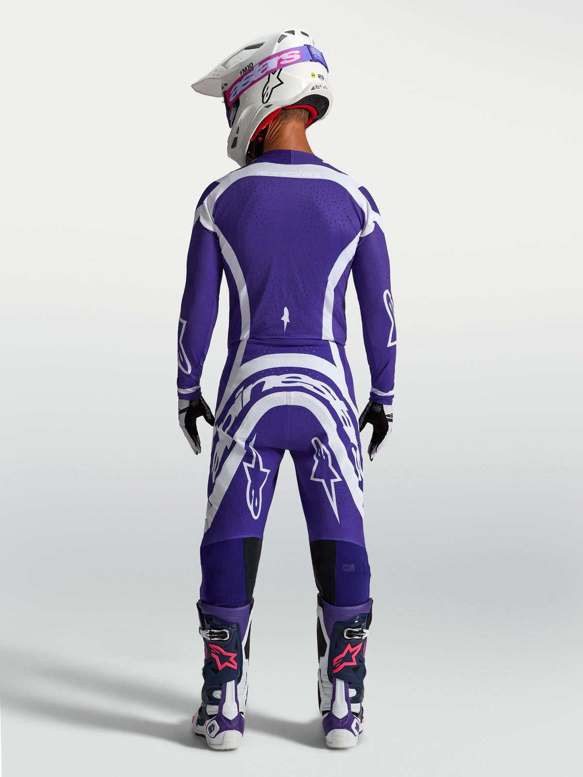 Alpinestars Supertech Vesta byxor och tröja, motocrossutrustning för herr, blå och vit, sedd bakifrån på modell med hjälm och stövlar för terrängkörning.
