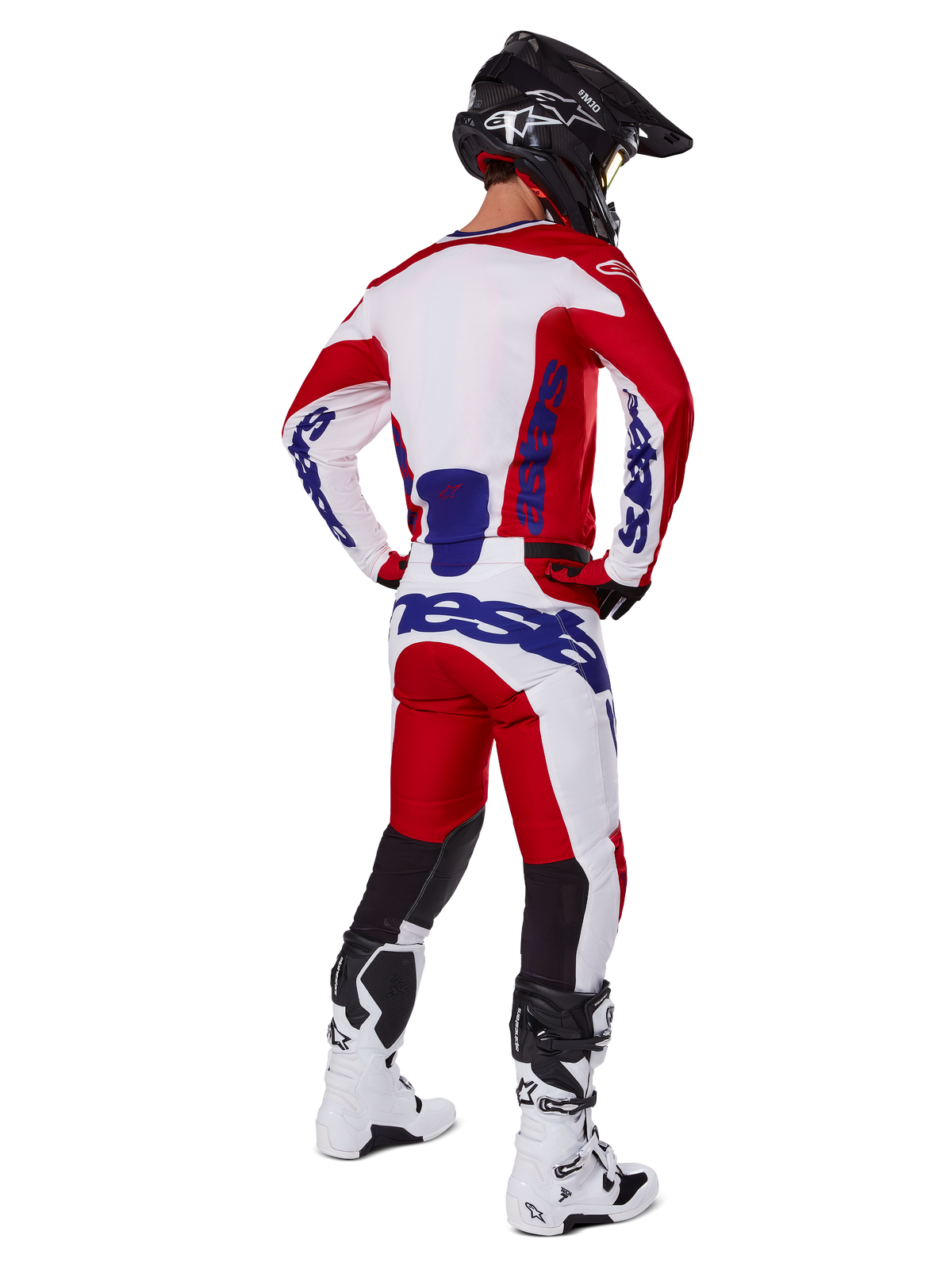 Alpinestars 2025 Racer Veil byxor, motocrossbyxor, klarröda och vita med blå detaljer, sedda bakifrån på en förare i full utrustning, framträdande Alpinestars-logotyp, ventilerande paneler på underbenen, matchande vita stövlar och svart hjälm.