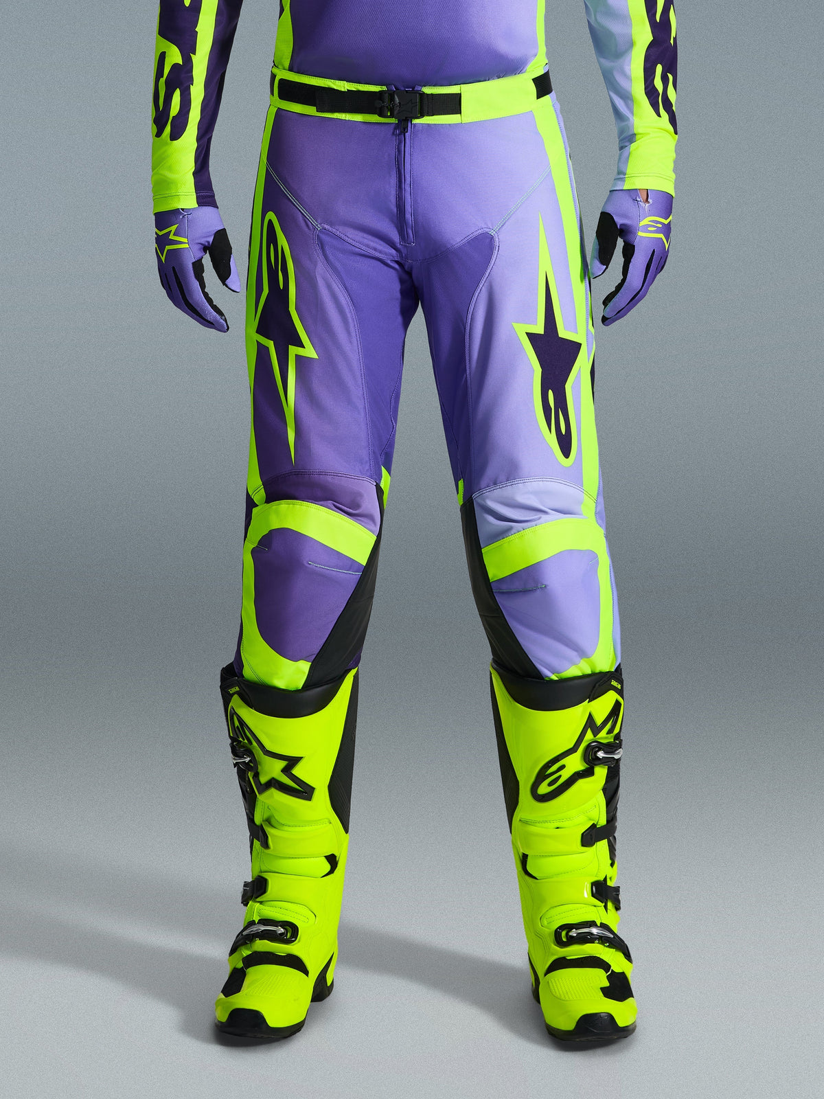Alpinestars 2026 Racer Portl Pants, Motocross Pants, Purple and Yellow Fluo, worn with matching fluo yellow boots and purple gloves, featuring large star logos and durable polyfabric construction for off-road racing