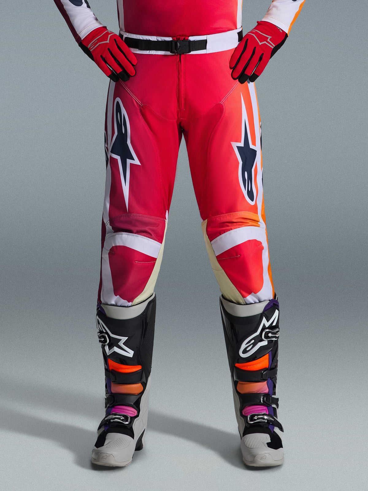 Alpinestars 2026 Racer Portl Pants, Motocross Pants, Red Light Gray and Dark Gray, worn with matching red gloves and multicolored boots, featuring bold Alpinestars star logos on the thighs and white accents, sporty design for off-road racing