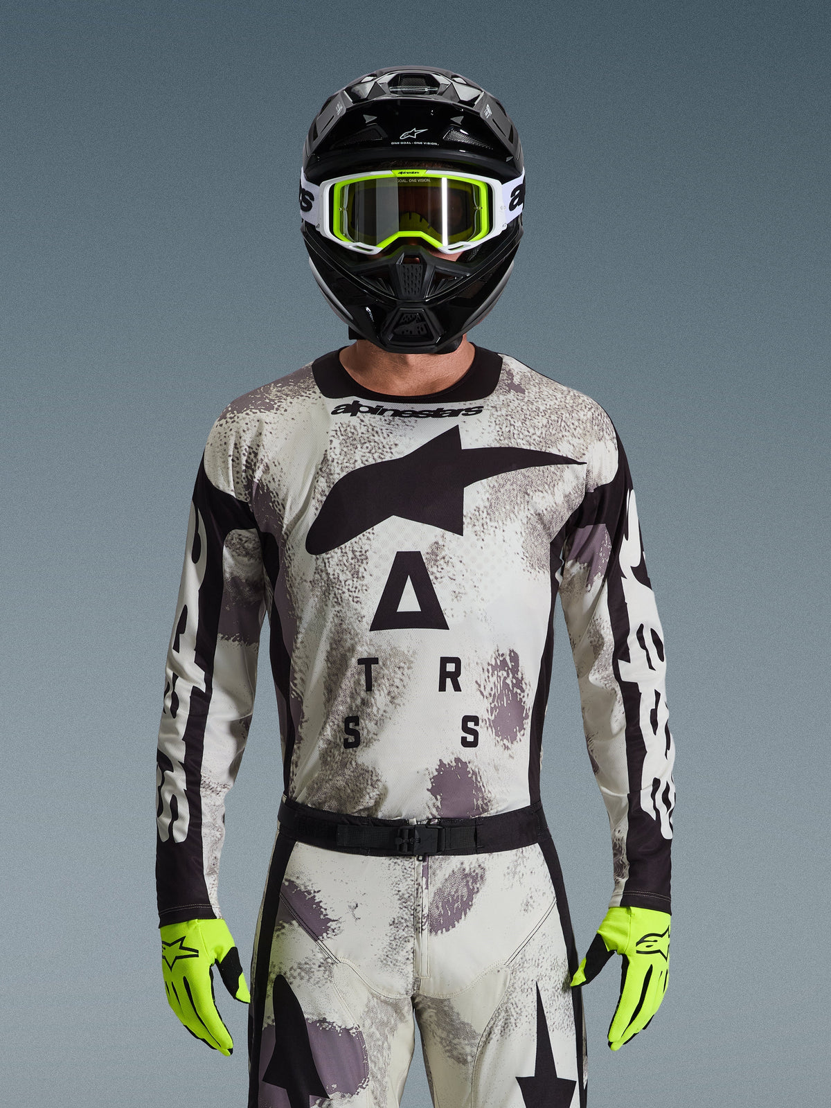 Alpinestars 2026 Racer Lahnd Jersey, Motocross Gear Set, Sand Camo pattern in gray and white, large black star logo and 'ASTARS' lettering, worn with black helmet, neon yellow goggles, and neon yellow gloves, professional off-road racing gear