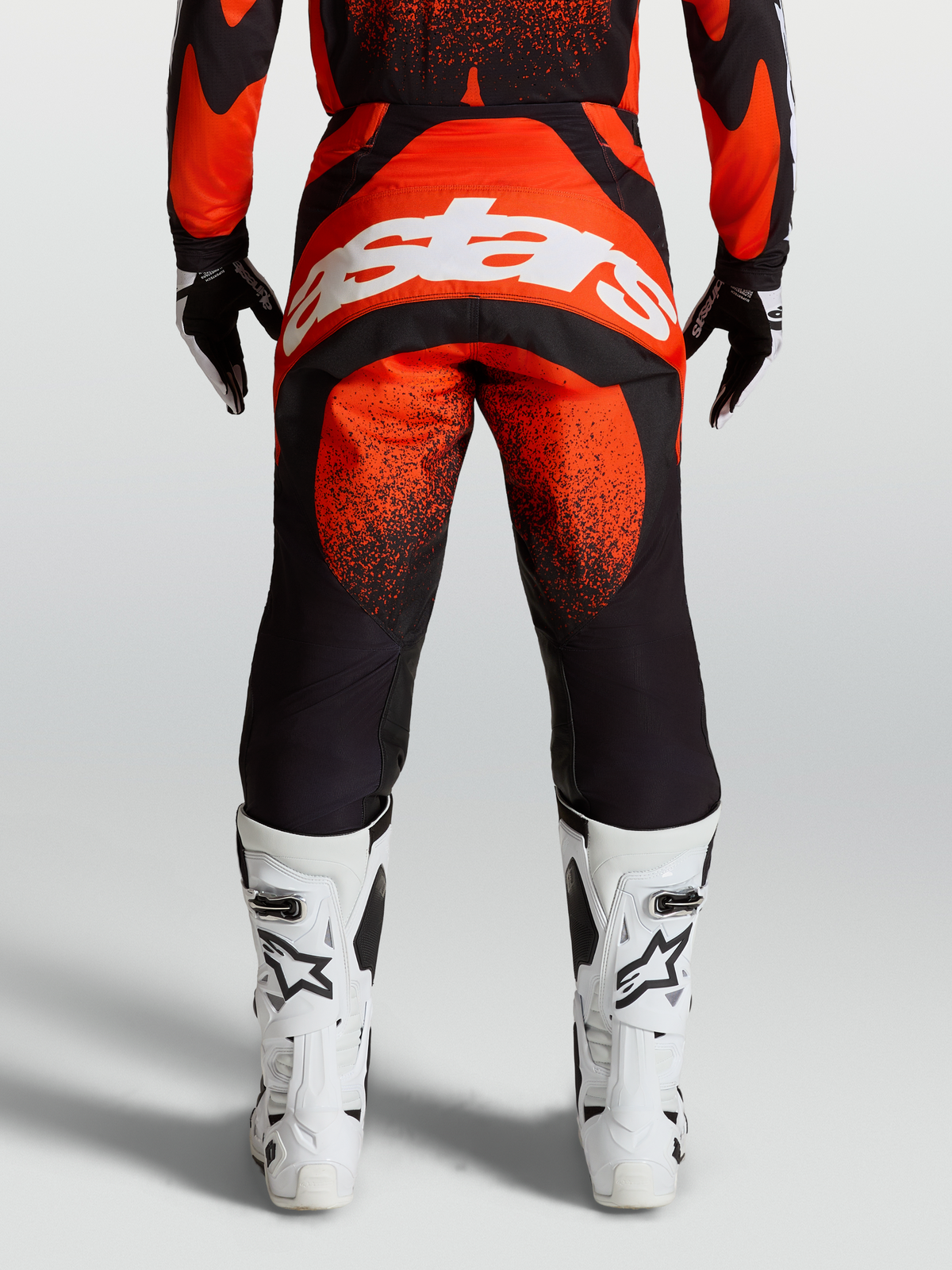 Alpinestars Techstar Swan byxor, motocrossbyxor i rött och svart, vy bakifrån på modell med vit logotyp och vita stövlar.