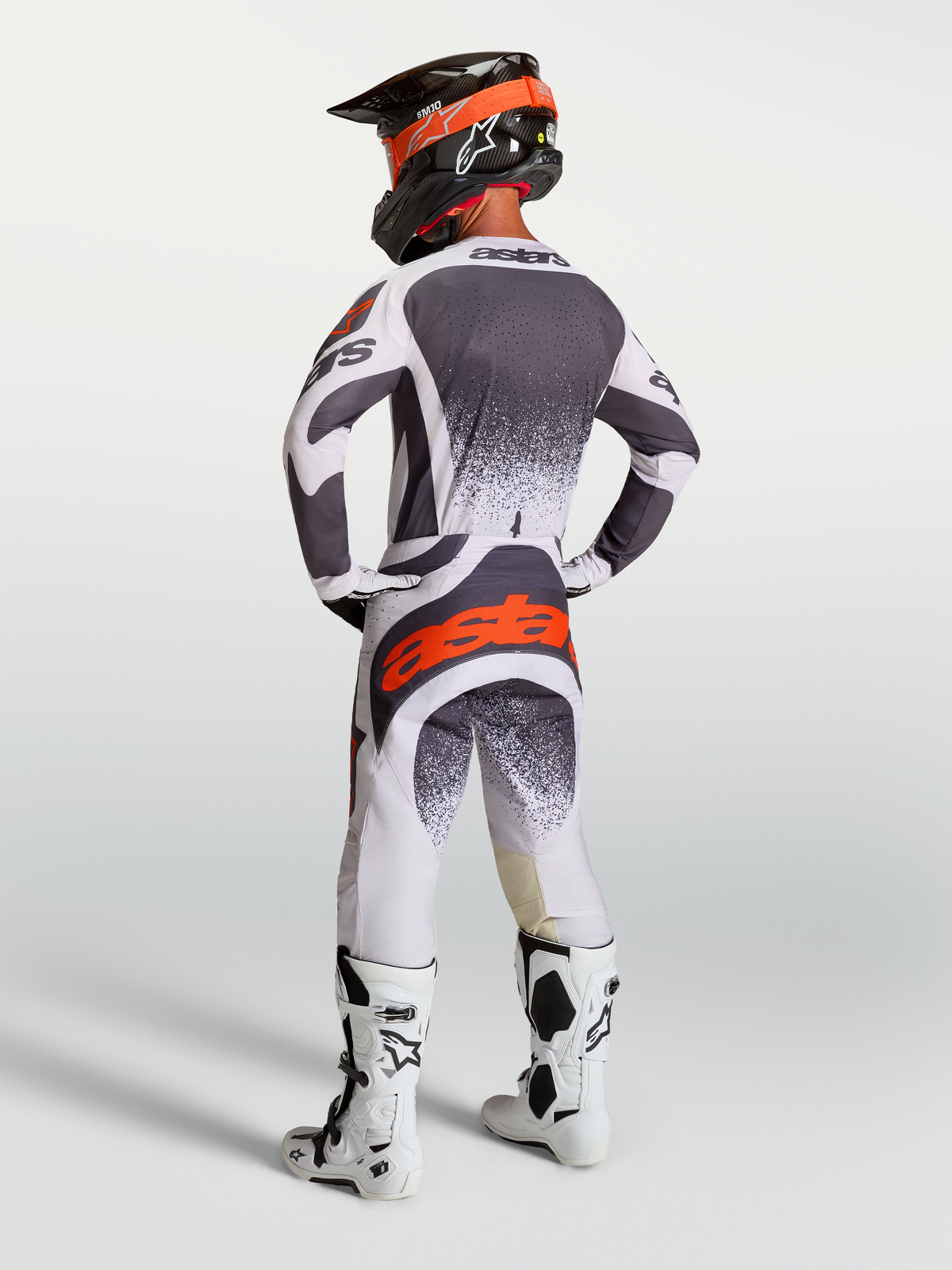 Alpinestars Techstar Swan byxor och tröja, motocrossutrustning för herrar, grå och vit med röda fluo-detaljer, vy bakifrån på modell, hållbar design för terrängkörning