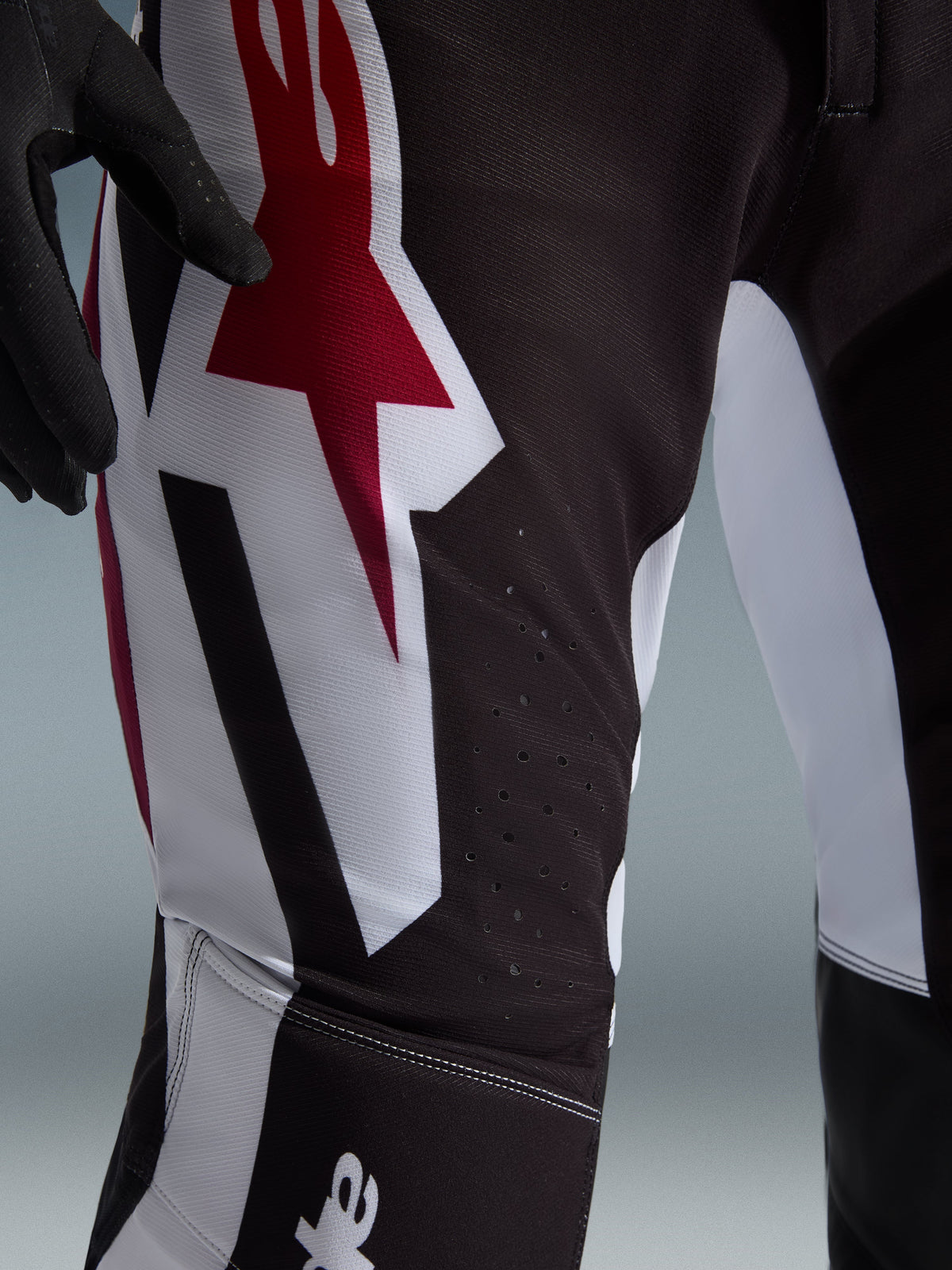 Alpinestars 2026 Supertech AFD Vista byxor, motocrossbyxor, svarta, röda och vita, närbild på låret med en stor röd och vit Astars-logotyp och laserskurna perforeringar för ventilation.
