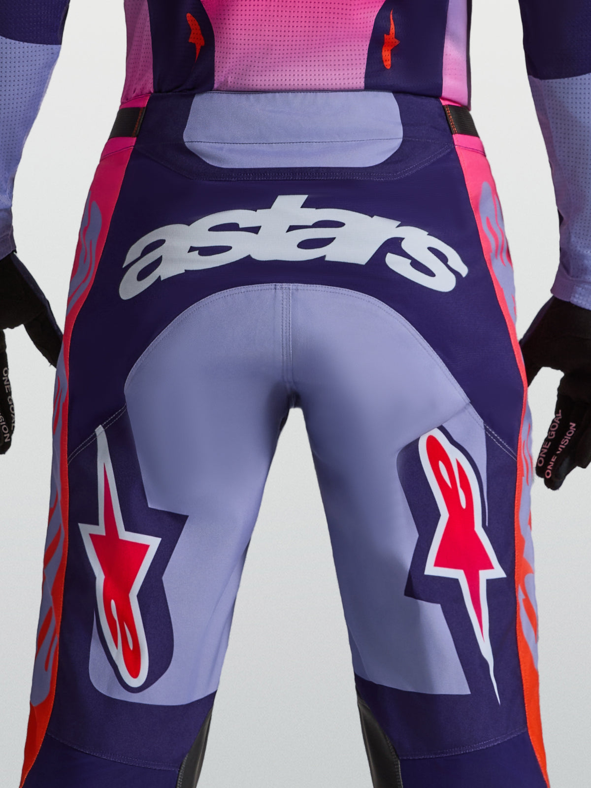 Alpinestars Racer Air Hunt byxor, lila och rosa motocrossbyxor, vy bakifrån på modell med astars-logotyp och ventilerad konstruktion.