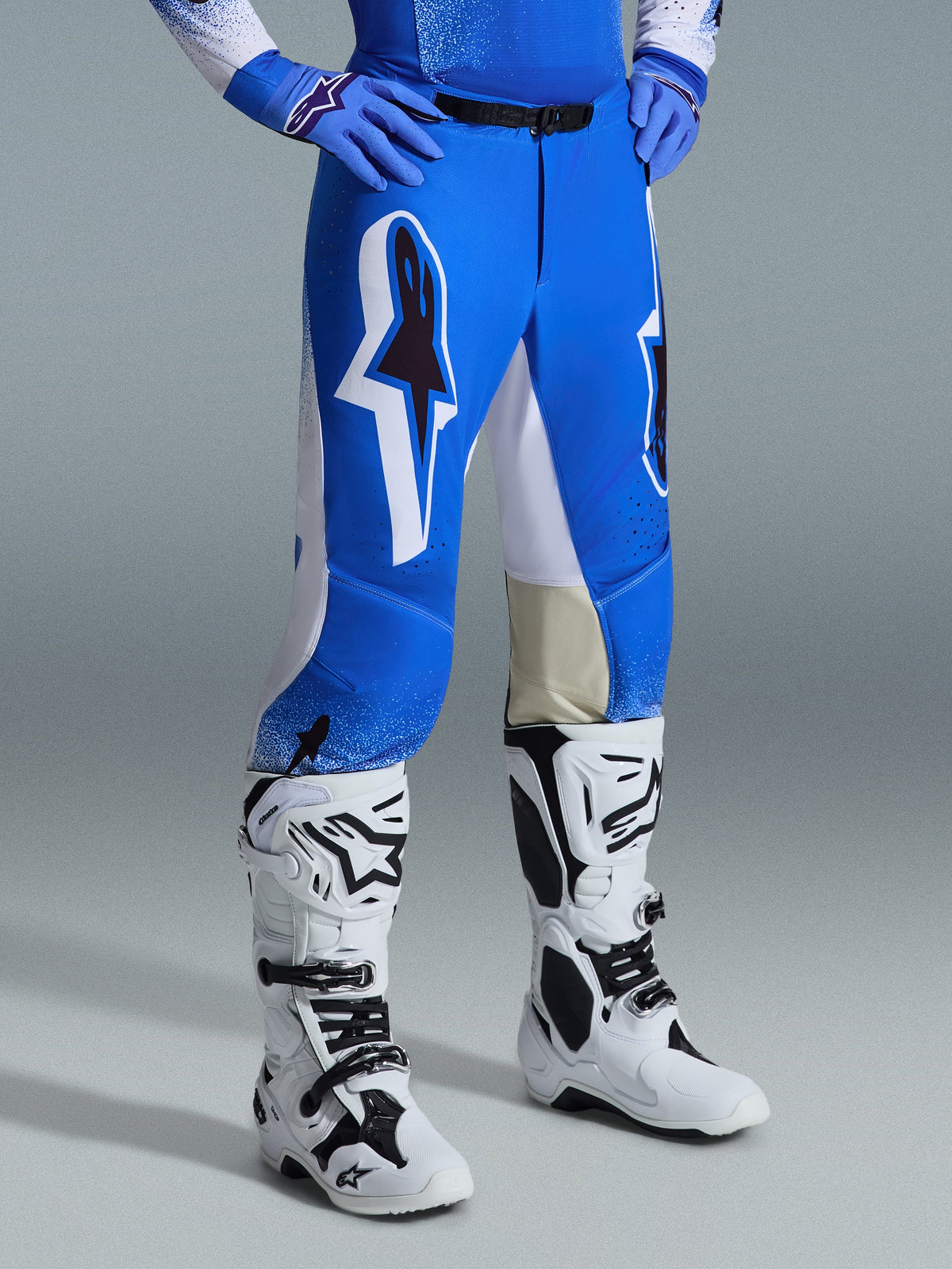Alpinestars 2026 Supertech Scenz-byxor, motocrossbyxor, Ucla Blue och vita, bärs med vita och svarta stövlar och blå handskar, med stora grafiska logotyper på låren och vita paneler, atletisk passform designad för tävlingsinriktad motocrosskörning