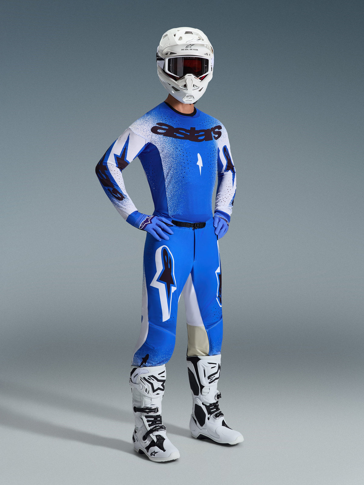 Motocrossförare i komplett racingutrustning, med 2026 Supertech Scenz-byxor i Ucla Blue och vitt, matchande blå och vit tröja med Astars-logotyp, vit hjälm med röda goggles samt vita och svarta stövlar, koordinerad outfit för professionell terrängkörning.