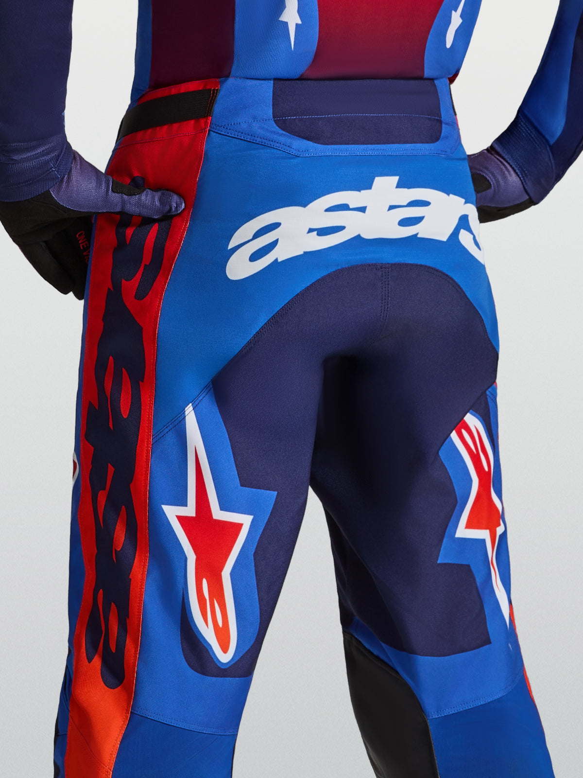 Alpinestars Racer Hunt byxor, blå och röda motocrossbyxor för herr med vit astars-logotyp och stjärngrafik, sedda bakifrån.