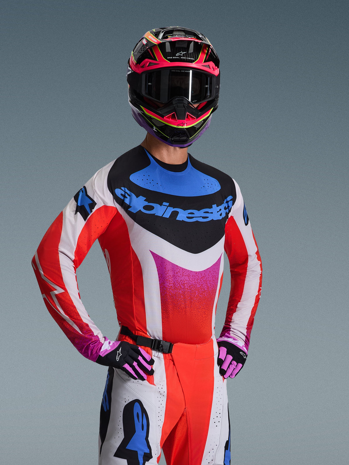 Alpinestars 2026 Techstar Knif-tröja, motocrosströja, vit med rött, blått och rosa gradientmönster, framträdande blå logotyp på bröstet, bärs med matchande hjälm och handskar, atletisk racingdesign för terrängkörning