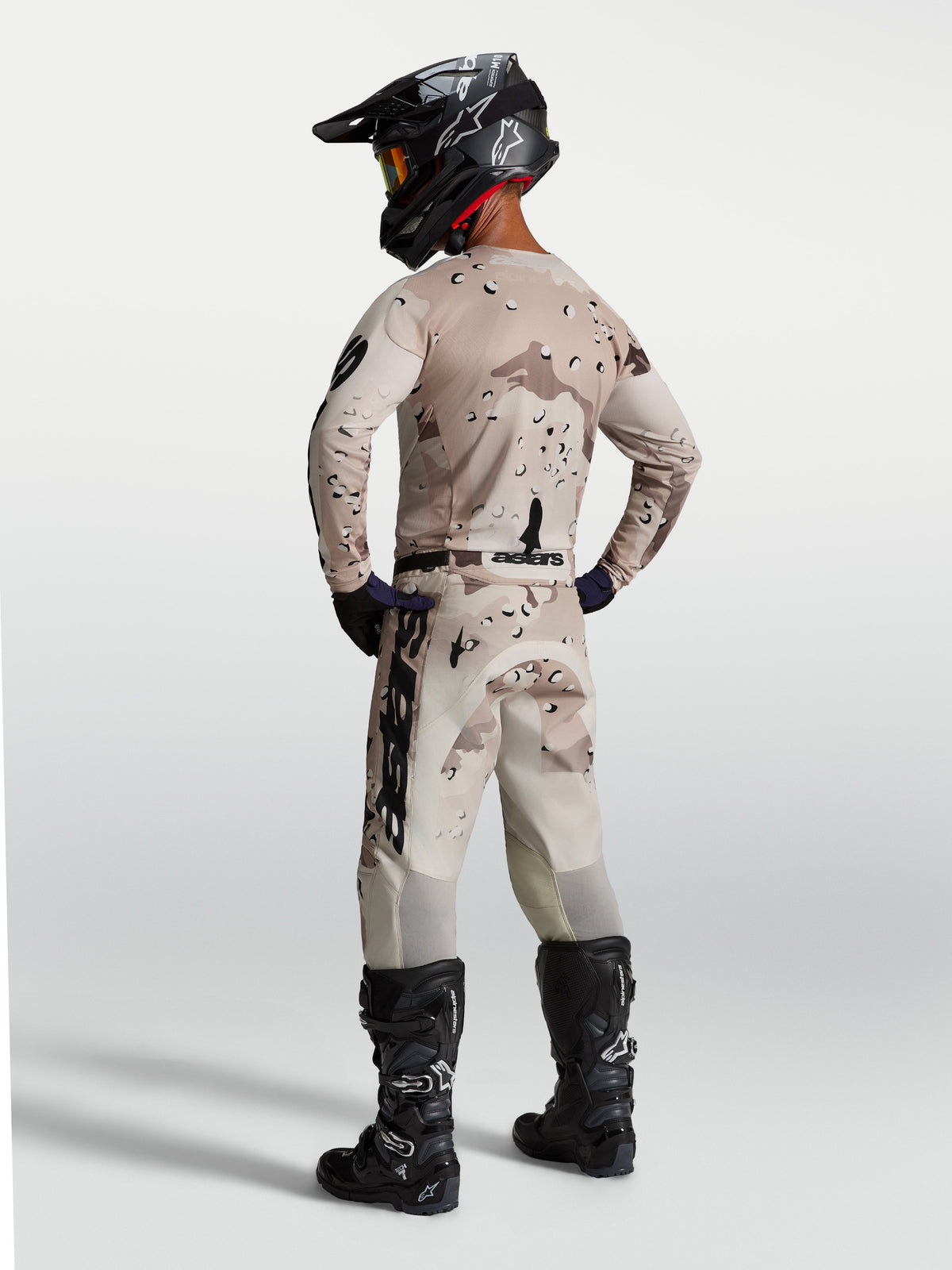 Alpinestars Racer Lone utrustningsset, sandfärgad kamouflagemönstrad motocrosströja och byxor sedda bakifrån med svarta motorcykelstövlar, för terrängkörning
