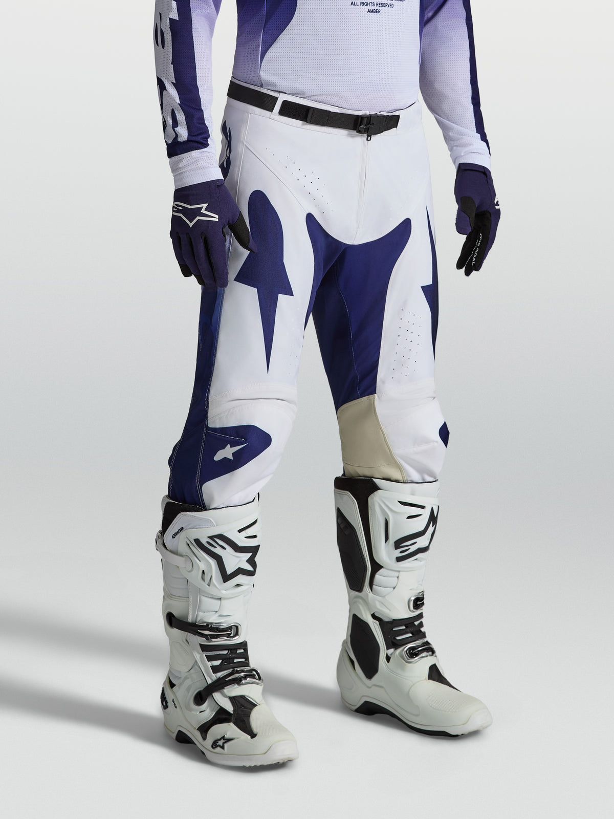 Alpinestars Racer Air Amber byxor, vita och blåa motocrossbyxor för herr, perforerat tyg, på modell med vita stövlar.