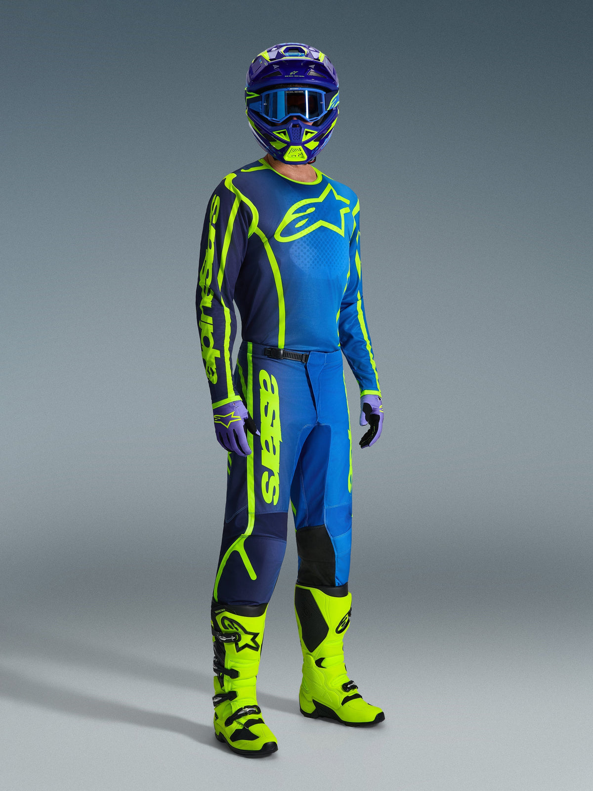Motocrossförare bär Alpinestars 2026 Fluid Apex-byxor i Blue Yellow Fluo, koordinerat med en matchande tröja, blå och gul hjälm och neongula stövlar, professionellt utrustningsset för motocross.