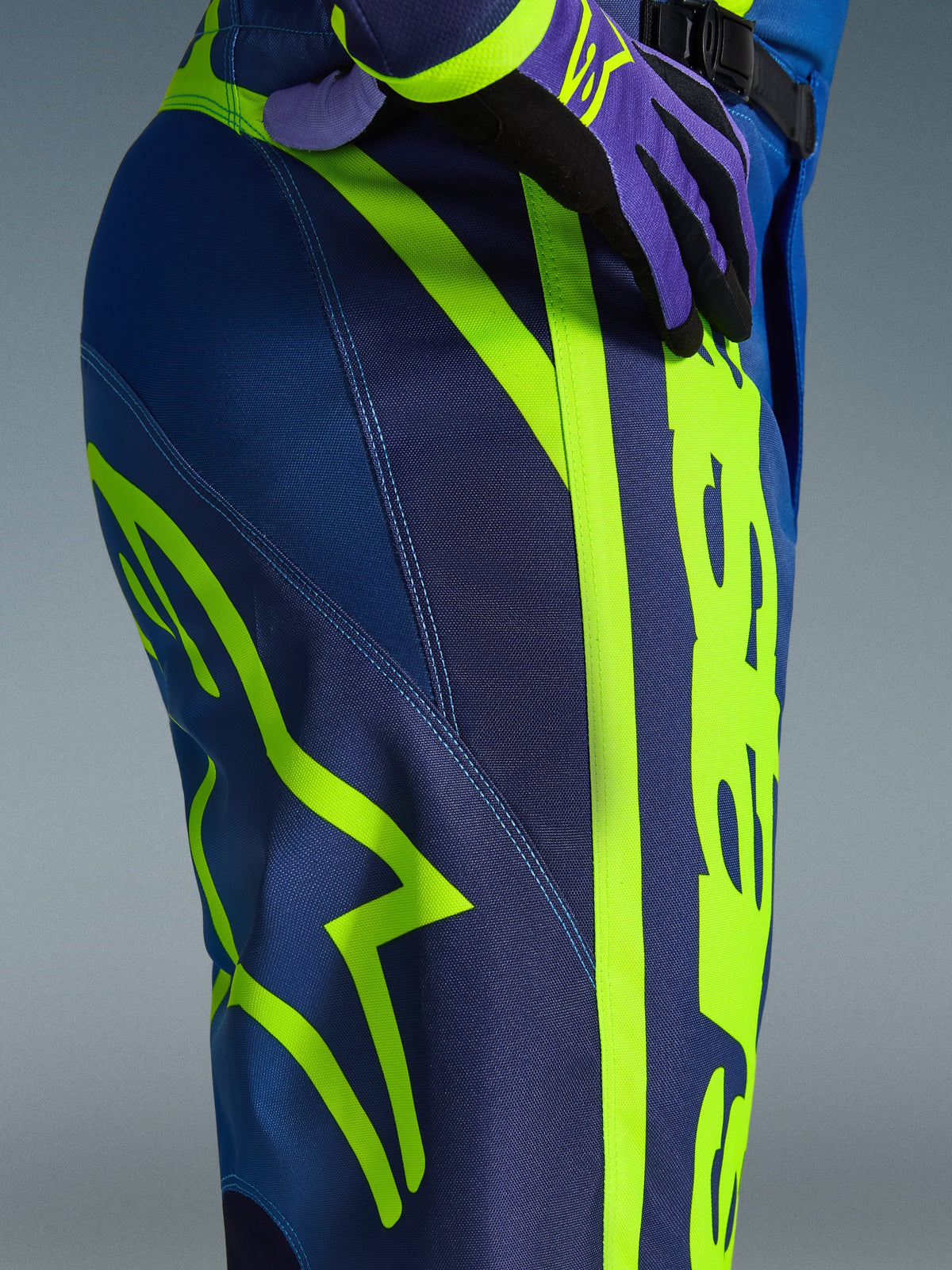 Alpinestars 2026 Fluid Apex byxor, motocrossbyxor, blå och neongula, närbild av sidan och höften med framträdande neongul Alpinestars-logotyp, slitstarkt polytyg för terrängkörning, del av matchande utrustningsset