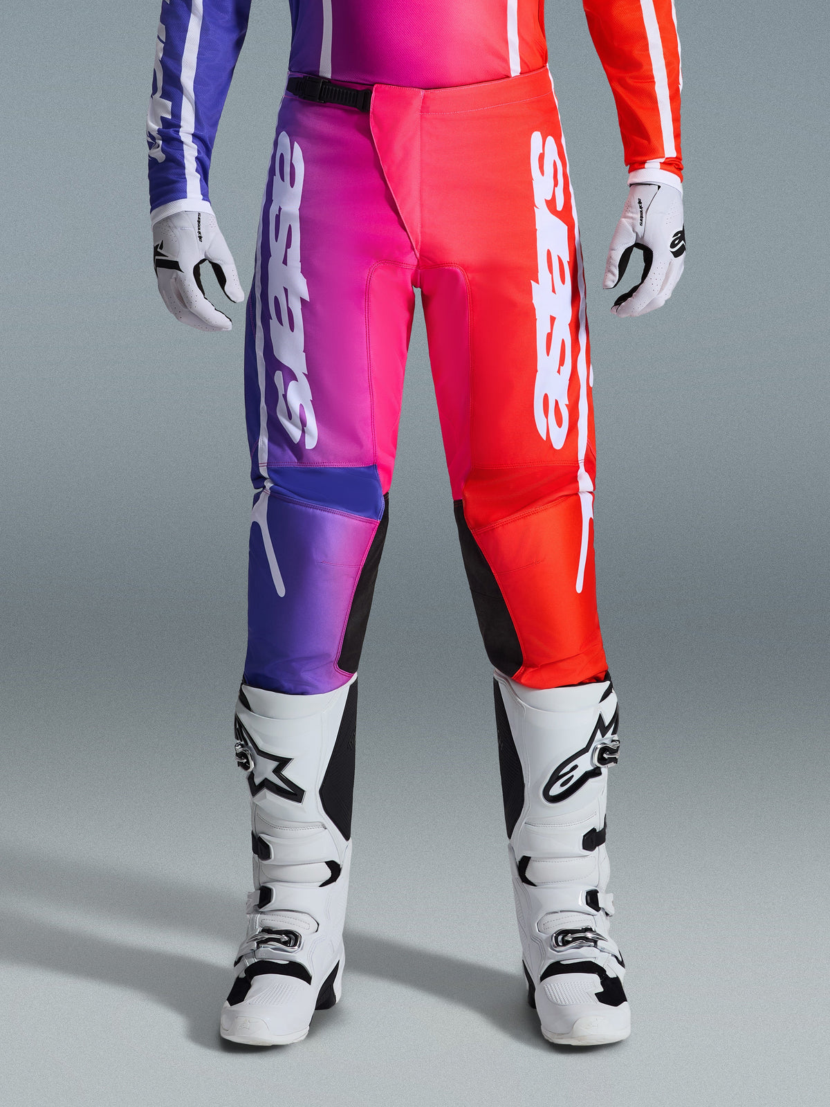 Alpinestars 2026 Fluid Apex byxor, motocrossbyxor, flerfärgad lila, rosa och röd gradientdesign, stora vita Alpinestars-logotyper på benen, kombineras med vita och svarta motocross-stövlar och handskar, professionell racingutrustning för terrängkörning