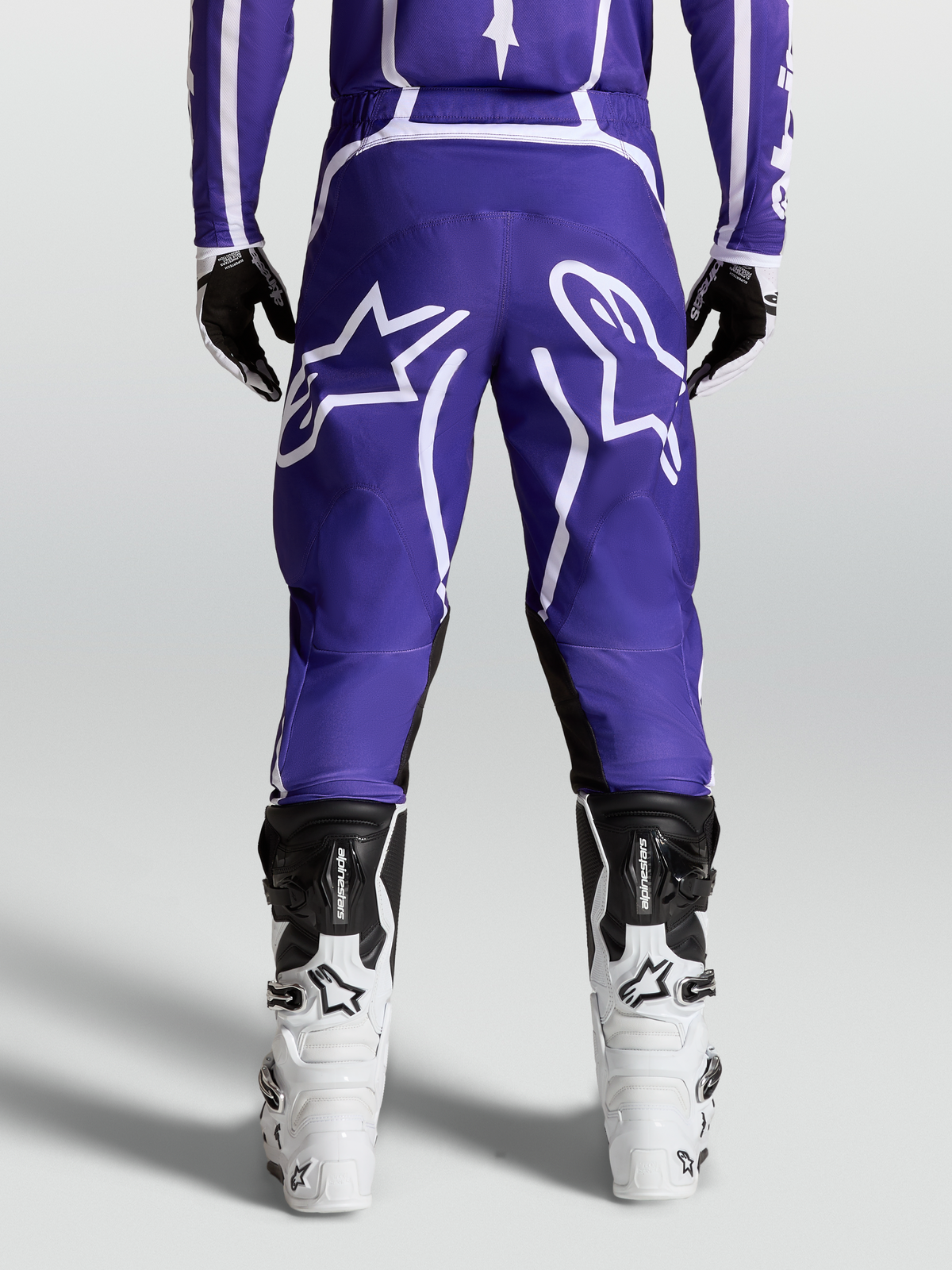 Alpinestars Fluid Apex V2 byxor, MX-byxor för herr, mörkblå och vita, hållbar 600D polytygskonstruktion med förböjda ben, vy bakifrån på modell med stövlar