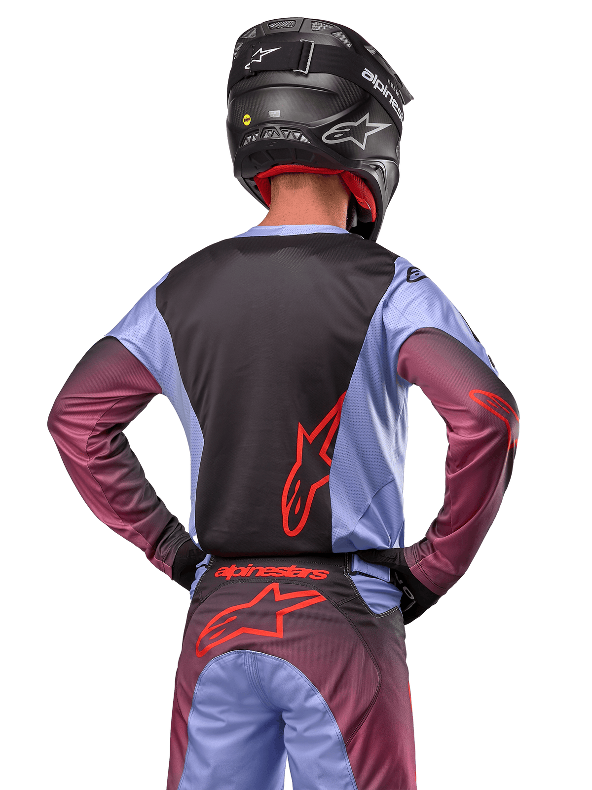 Motocrossförare sedd bakifrån iförd Alpinestars 2024 Racer Hoen-utrustning, Lavan Purple och svart tröja med röd logotyp, matchande byxor med röda detaljer, svart hjälm, koordinerad outfit för terrängkörning