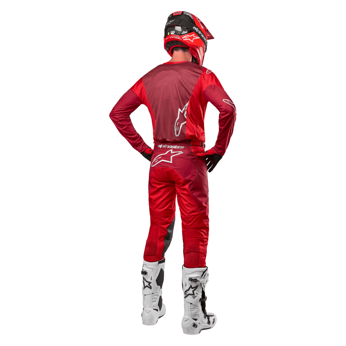 Alpinestars 2024 Racer Hoen-byxor och matchande tröja i Mars Red Burgundy, bakifrån vy av en motocrossförare i full utrustning med röd hjälm och vita stövlar, atletisk passform och logotypdetaljer för terrängkörning