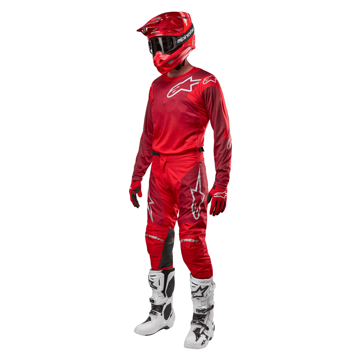 Motocrossförare i komplett racingutrustning, Alpinestars 2024 Racer Hoen byxor och tröja i Mars Red Burgundy, röd hjälm, röda handskar och vita och svarta stövlar, matchande outfit för terrängkörning
