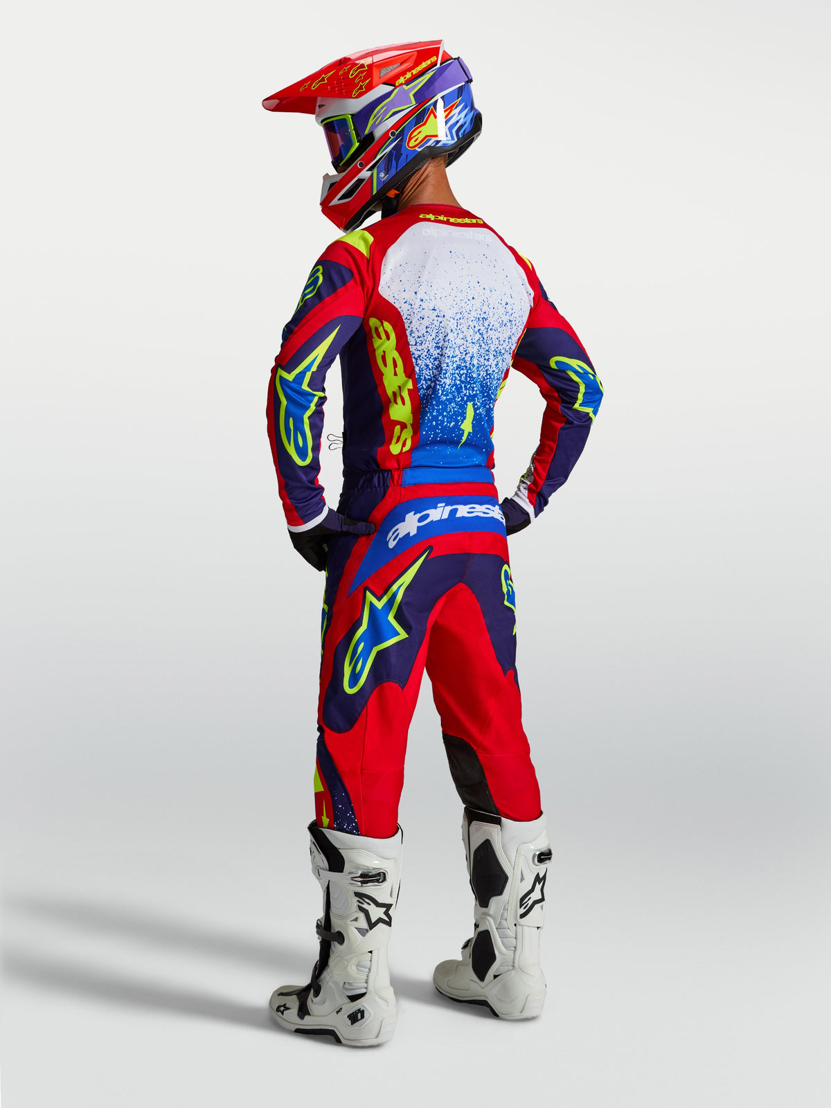 Alpinestars Fluid Drag byxor och 2027 gear set, blå och röd motocrossutrustning för herrar, vita stövlar, vy bakifrån.