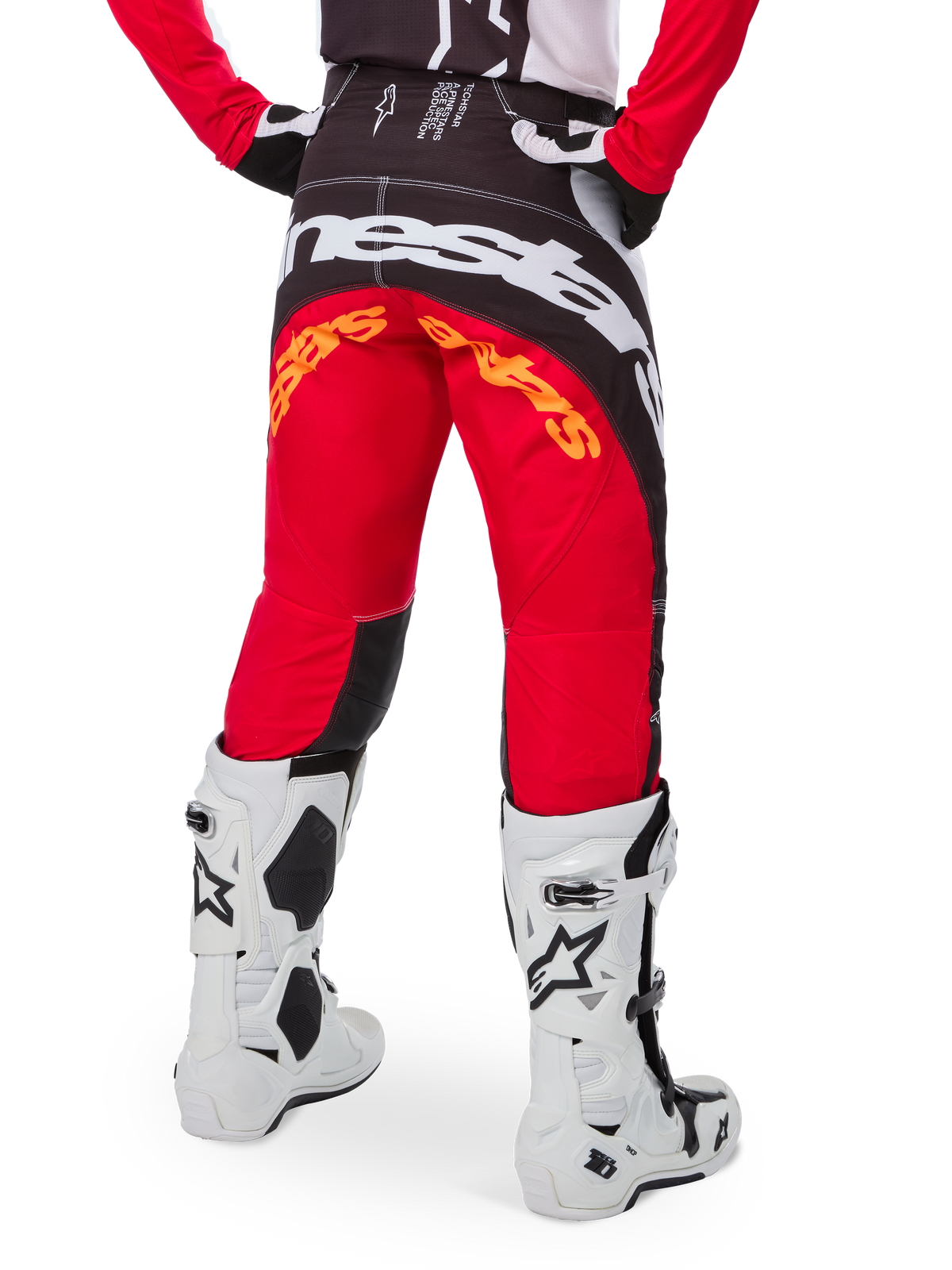 Alpinestars Limiterad Upplaga Techstar Deep-byxor, motocrossbyxor, svart, vit och High Red, vy bakifrån med stor vit Alpinestars-logotyp över sätet och orange detaljer, bärs med vita tekniska stövlar för professionell terrängkörning.